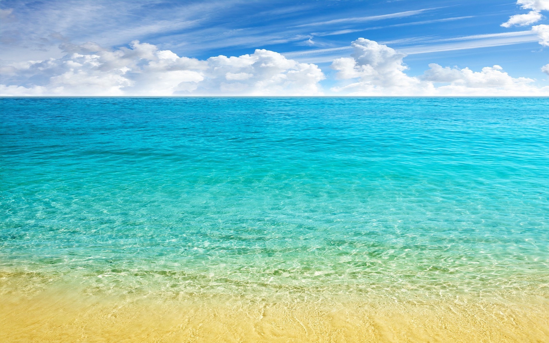 Turquoise ocean meeting a sandy beach under a cloudy blue sky HD Wallpaper