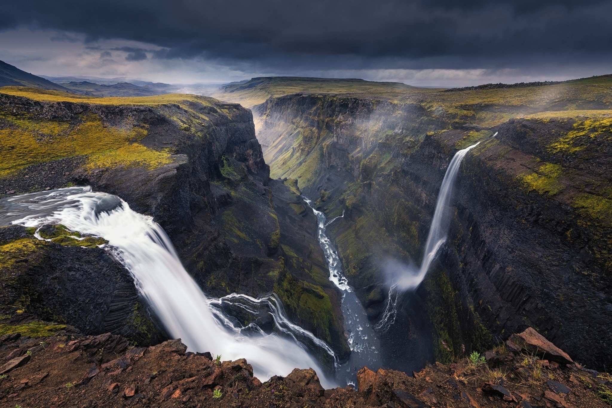 Waterfall canyon with dark clouds in Iceland HD Wallpaper