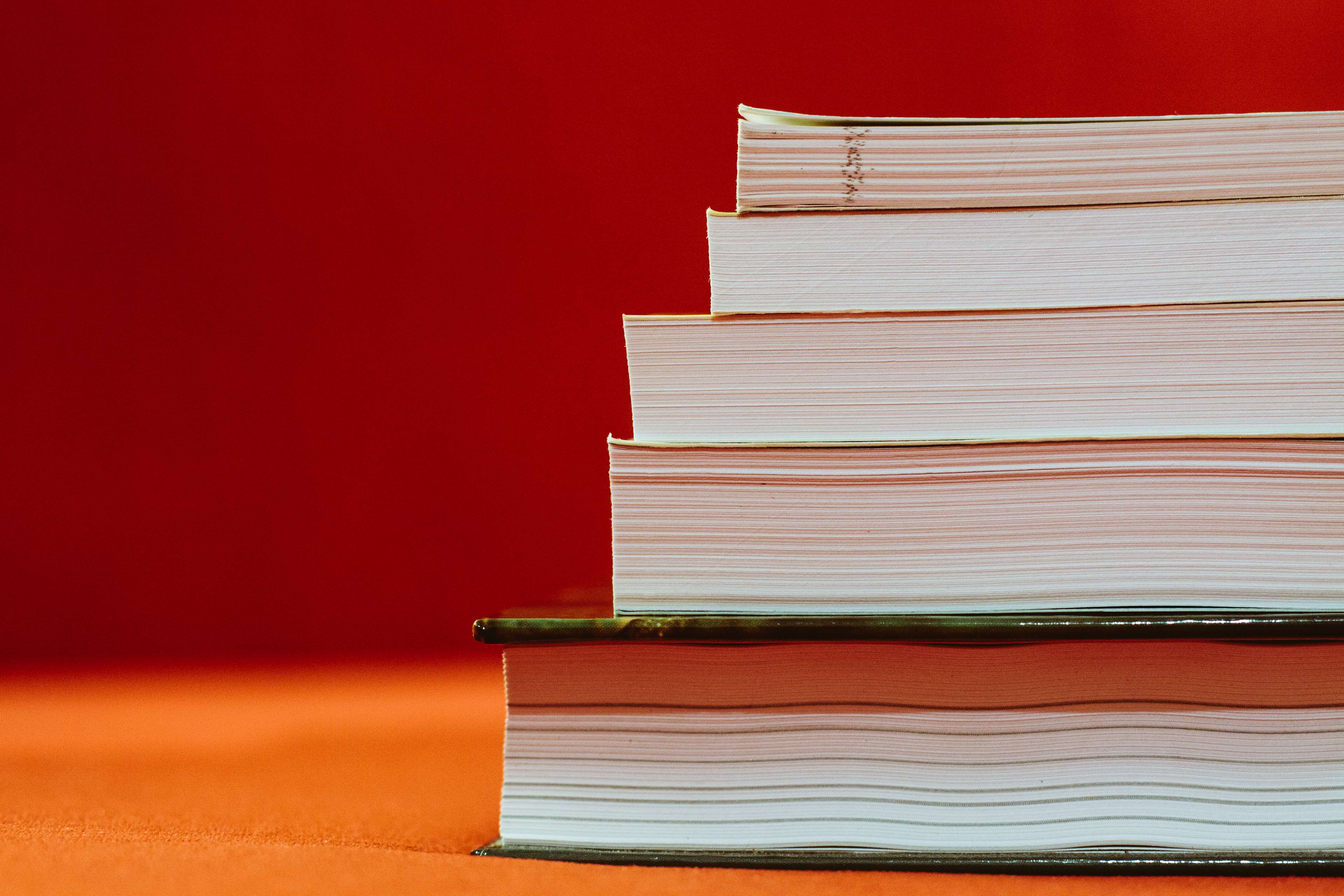 Stack of books on red background 4K HD Wallpaper