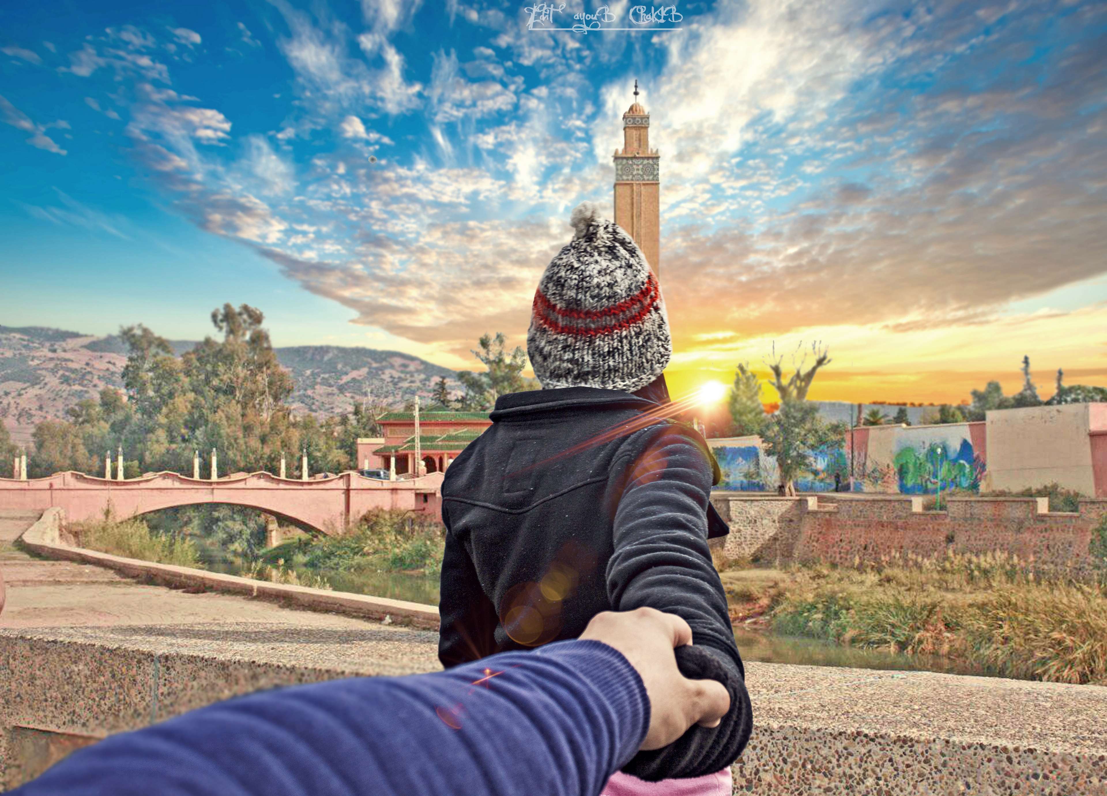 Couple holding hands at sunset near a tower HD Wallpaper