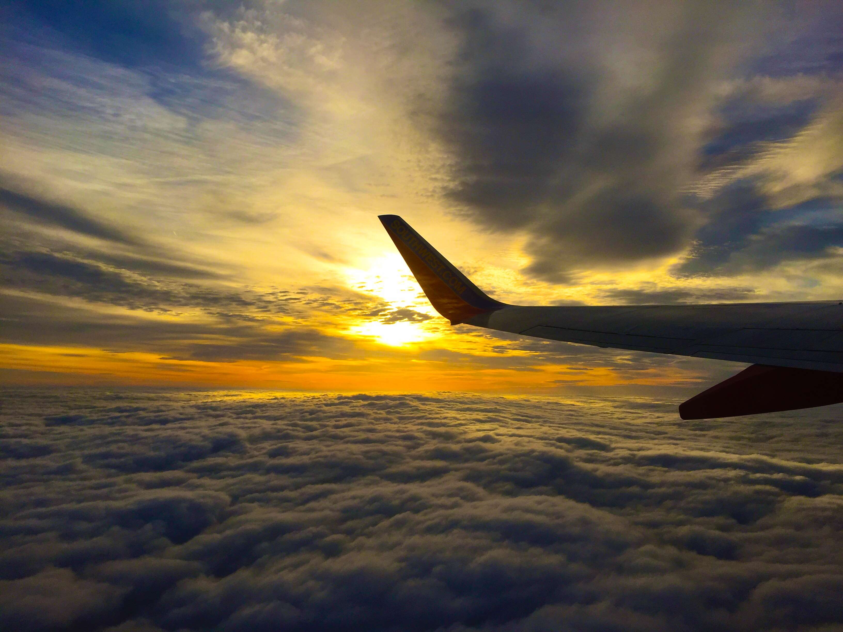 Airplane wing over clouds at sunset HD Wallpaper