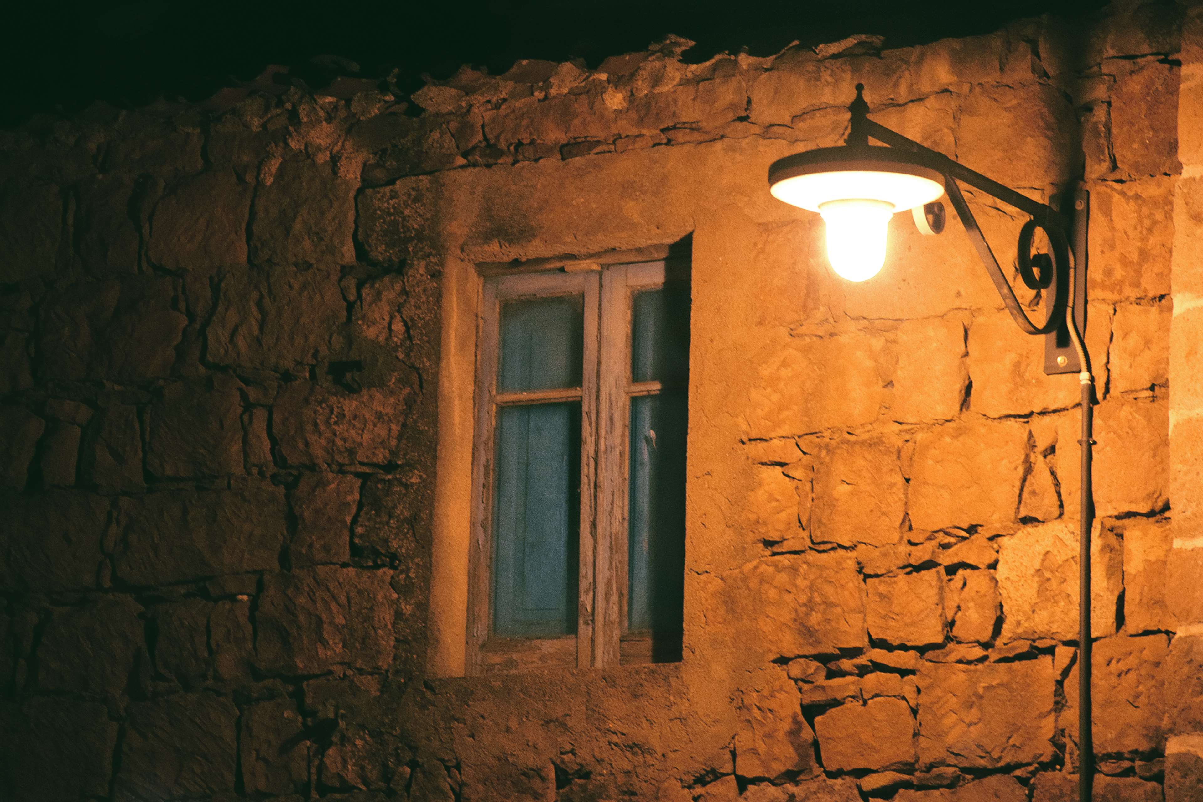 Old stone house with a window and a lamp at night HD Wallpaper