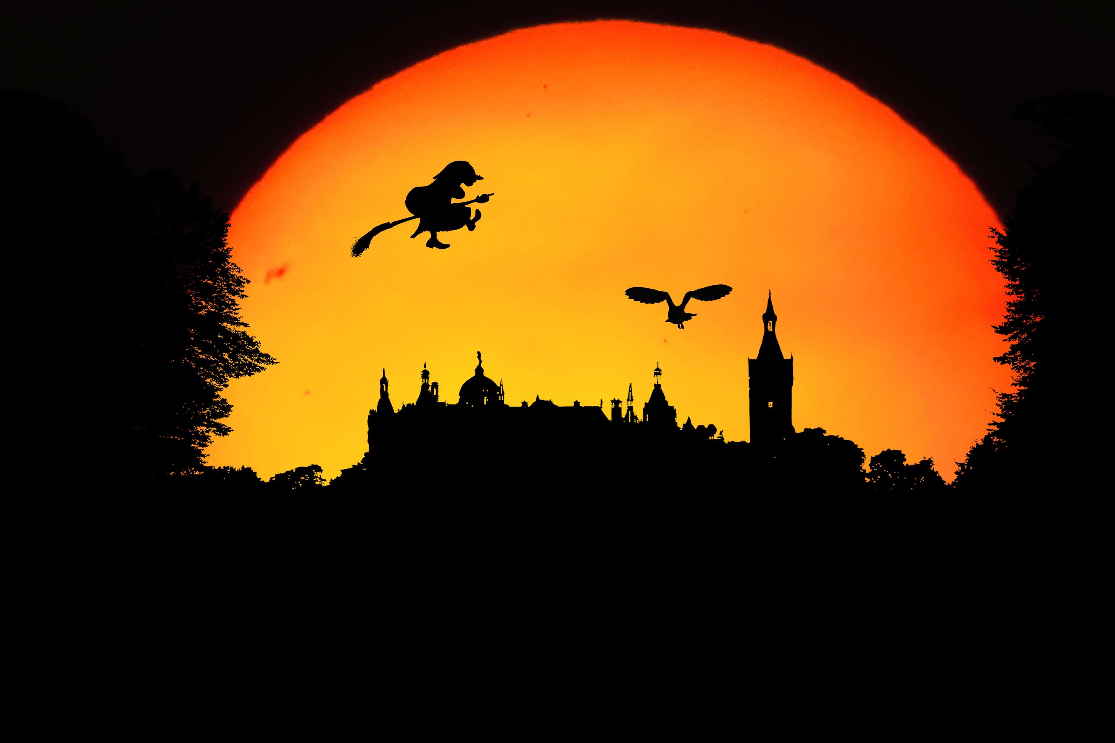 Silhouette of a witch flying on a broomstick with an owl over a castle at sunset HD Wallpaper