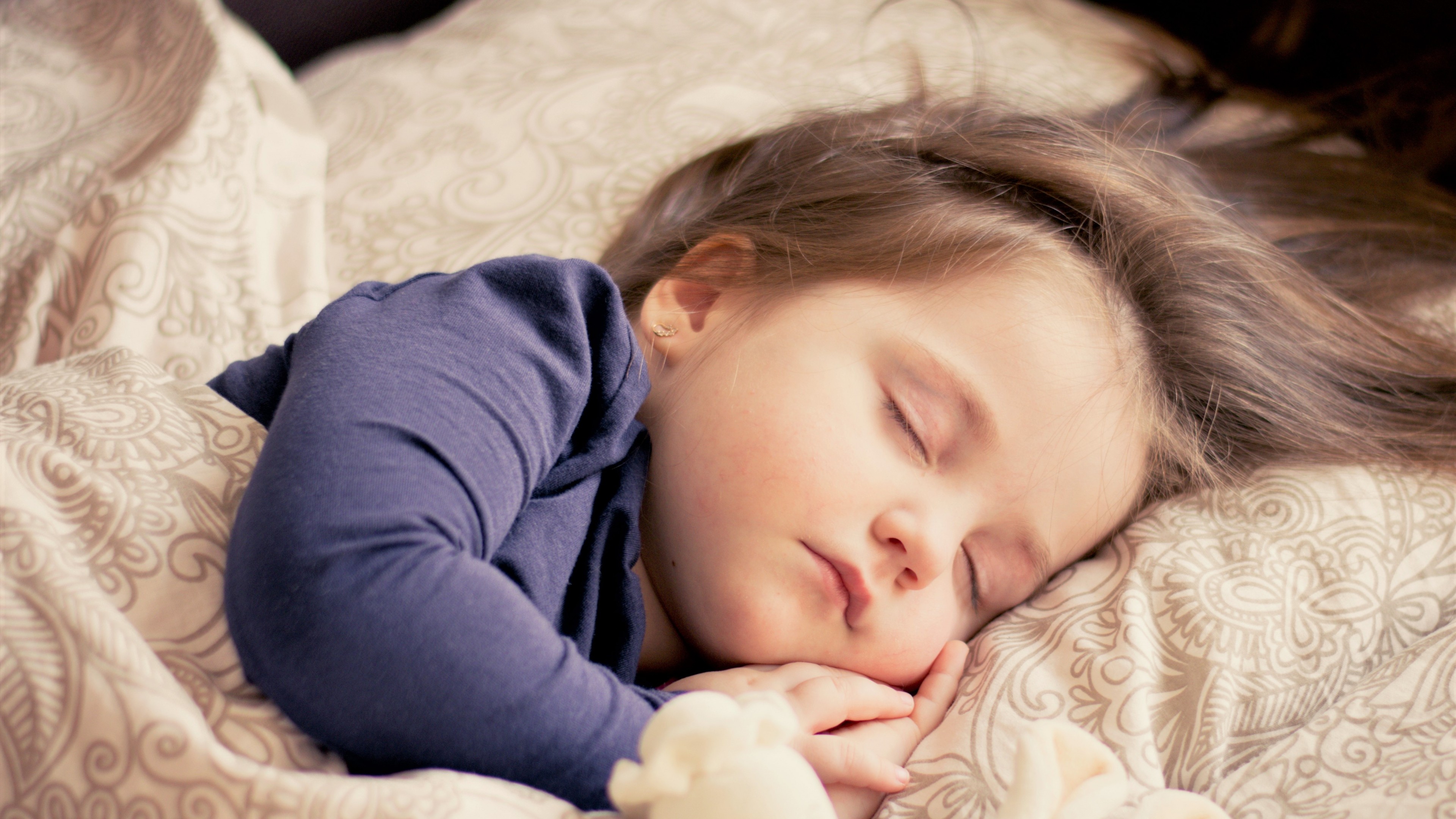 A young girl sleeping peacefully in bed HD Wallpaper
