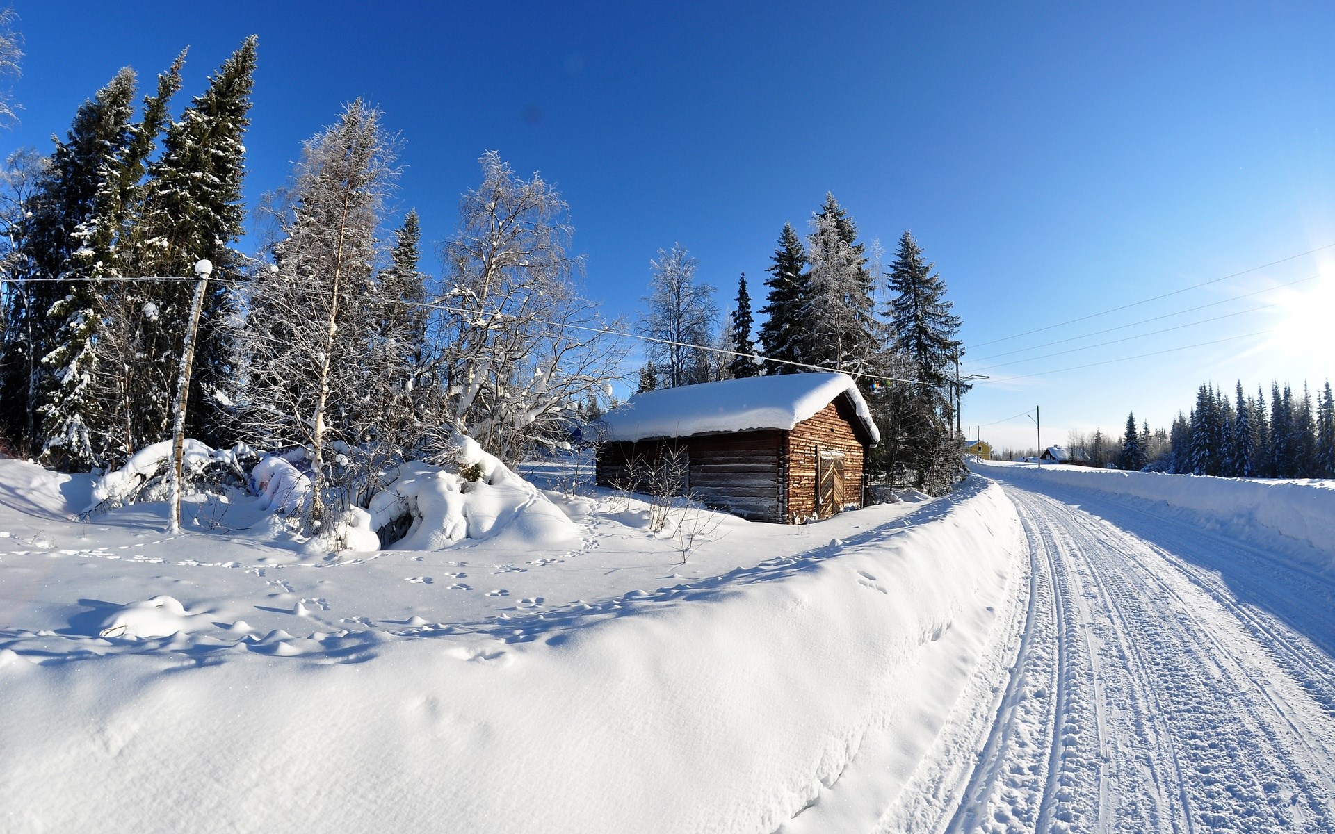 Snowy road next to a wooden cabin in winter HD Wallpaper