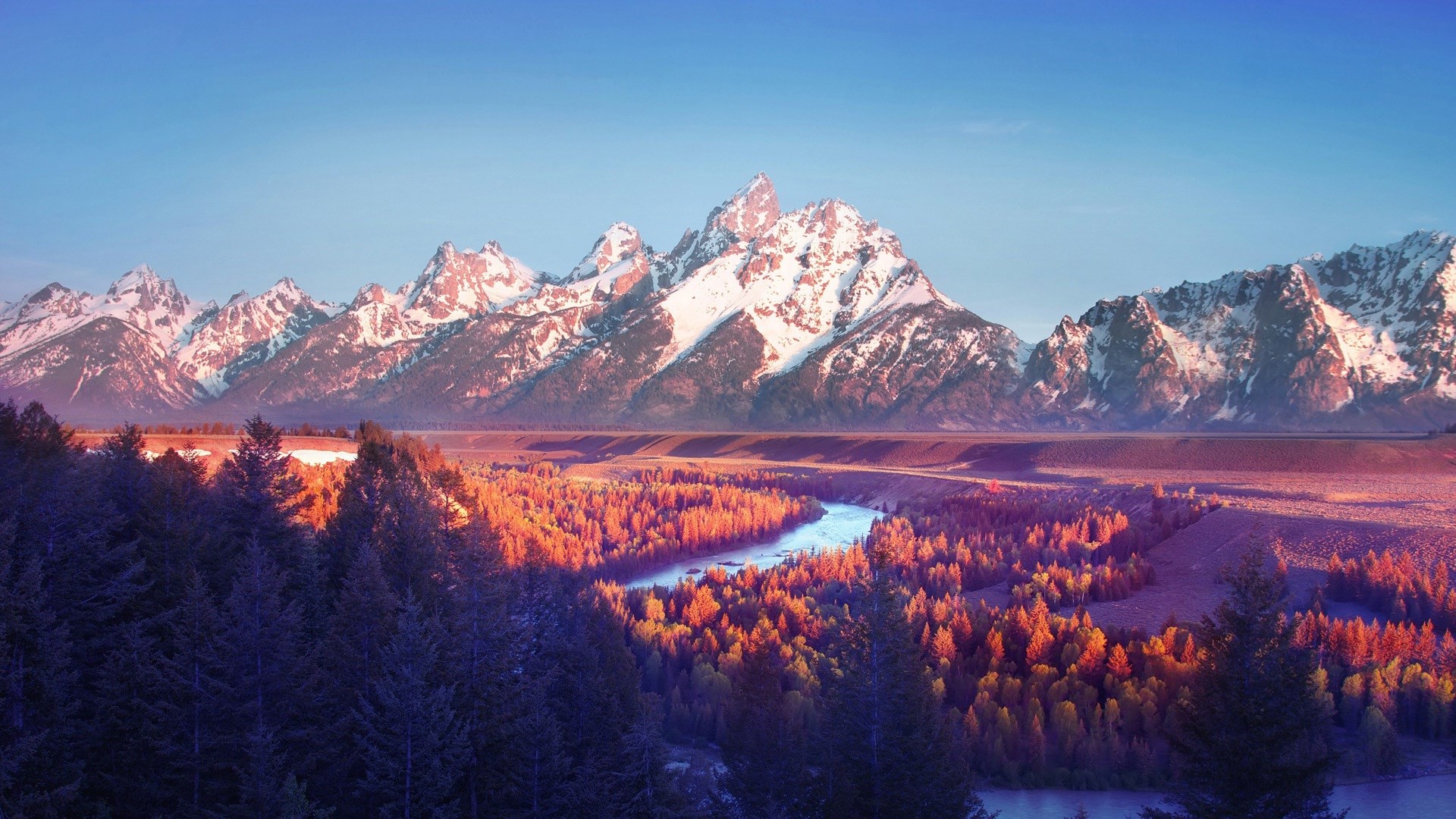 Snow-capped mountains over a forest and river HD Wallpaper
