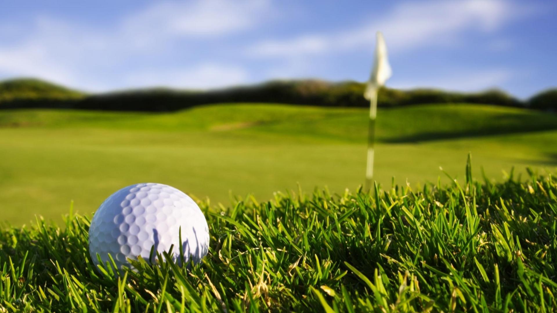 Golf ball on a golf course with a flag HD Wallpaper