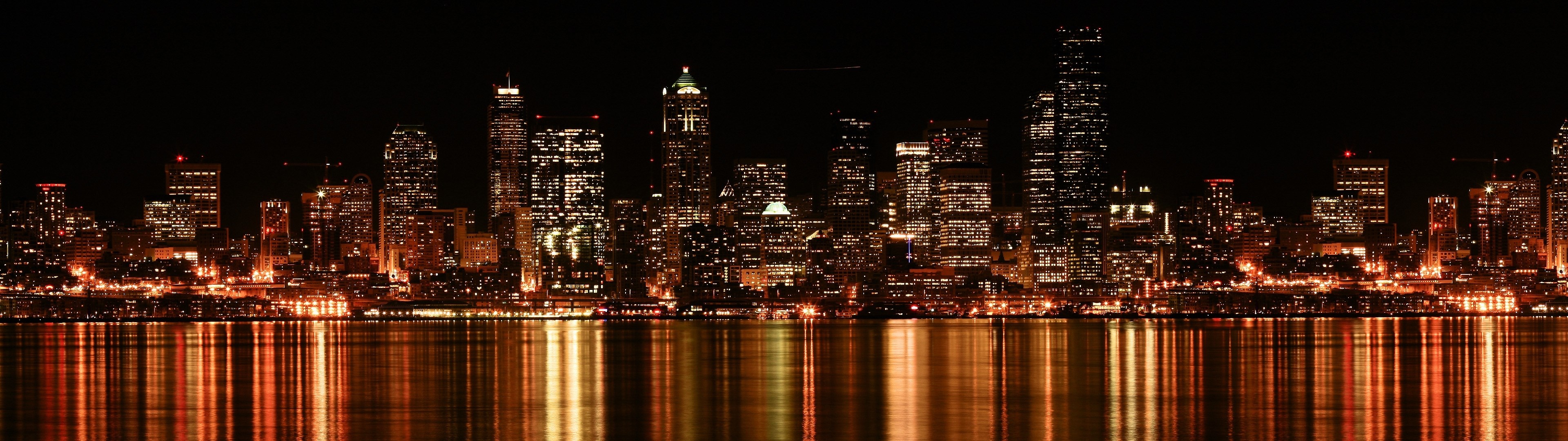 City skyline at night with water reflection HD Wallpaper