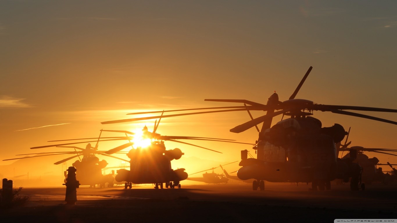 Helicopters silhouetted against a sunset HD Wallpaper
