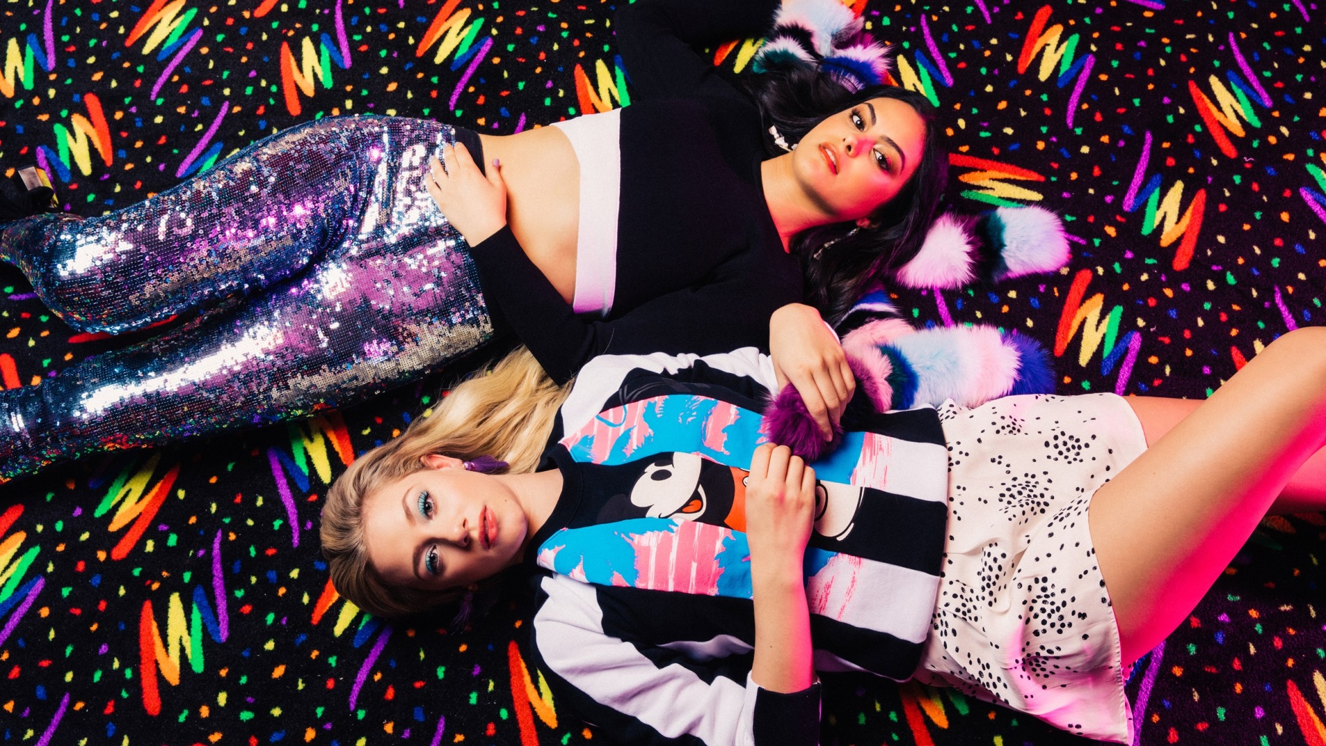 Two women lying on a colorful carpet HD Wallpaper