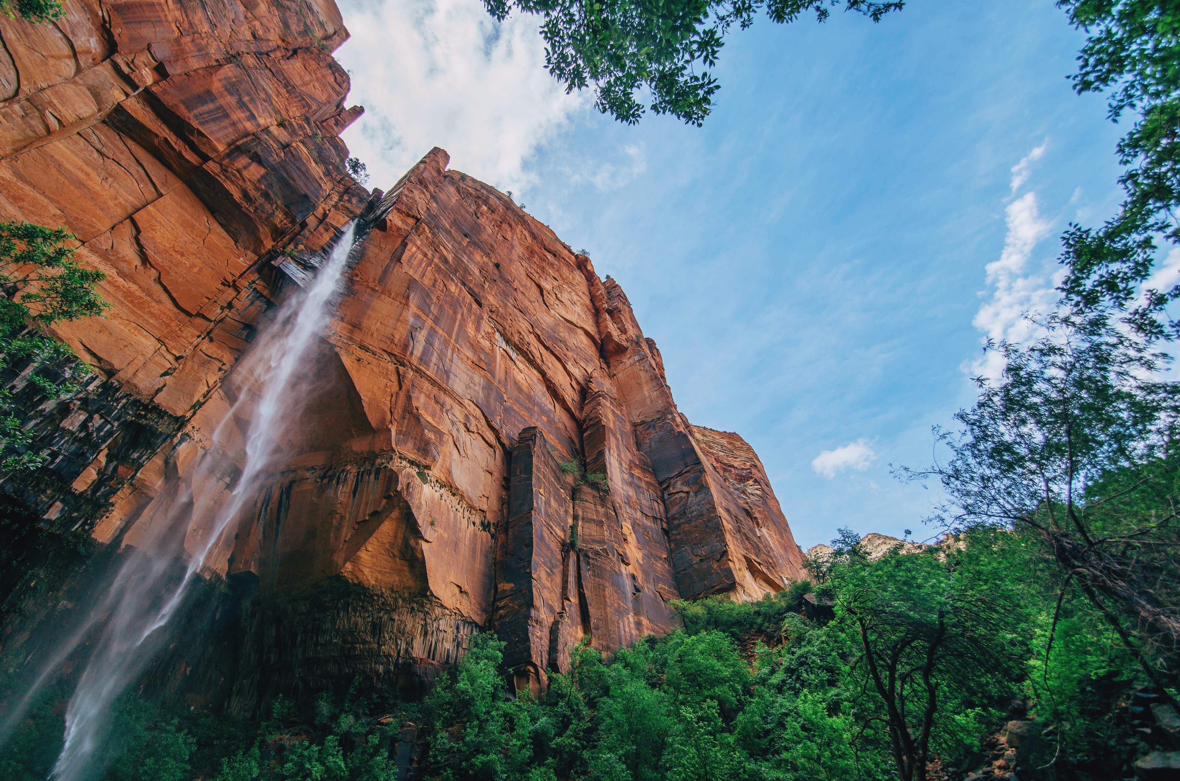Waterfall cascading down a massive sandstone cliff face HD Wallpaper
