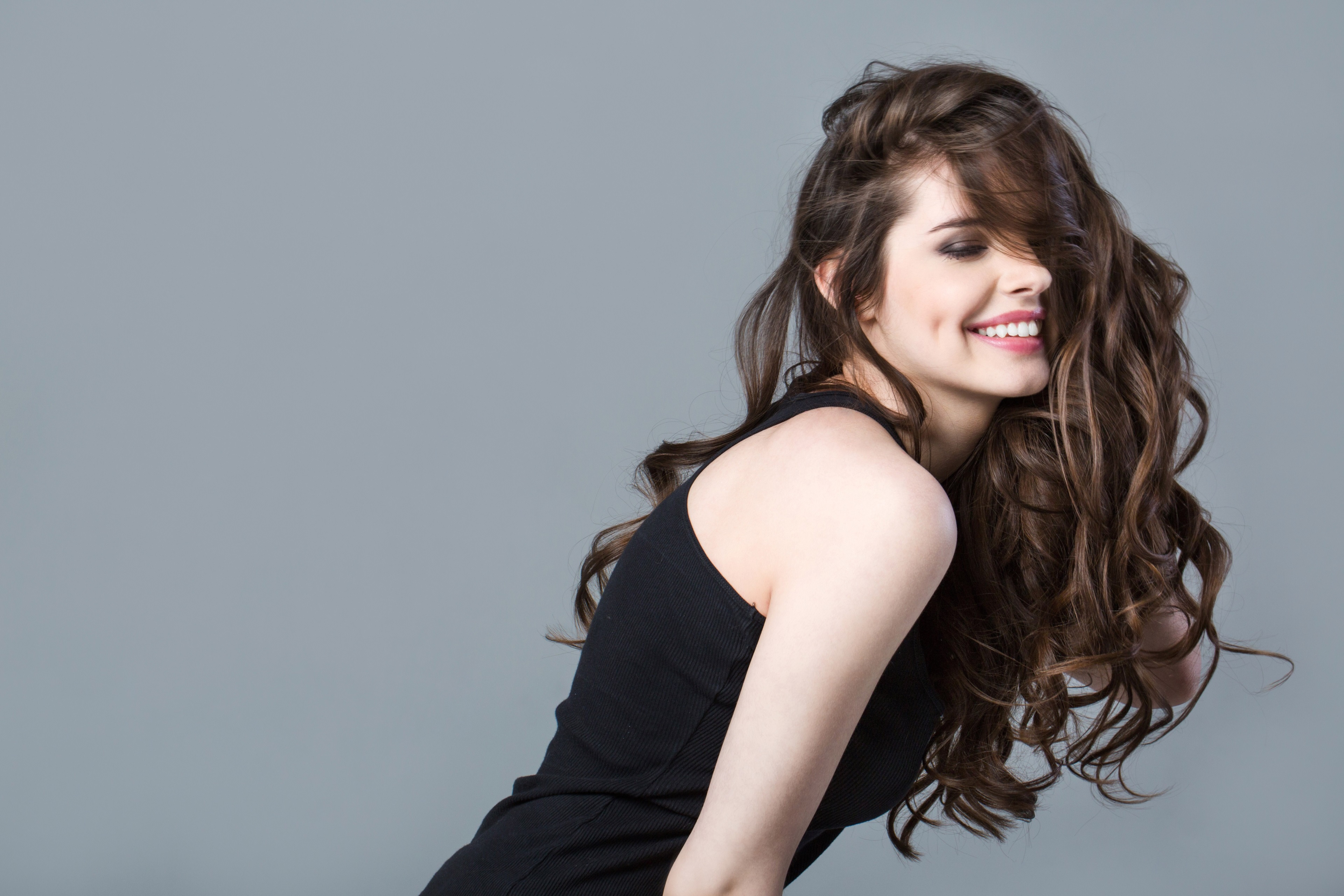 Smiling Woman with Long Curly Hair in Black Top 4K HD Wallpaper
