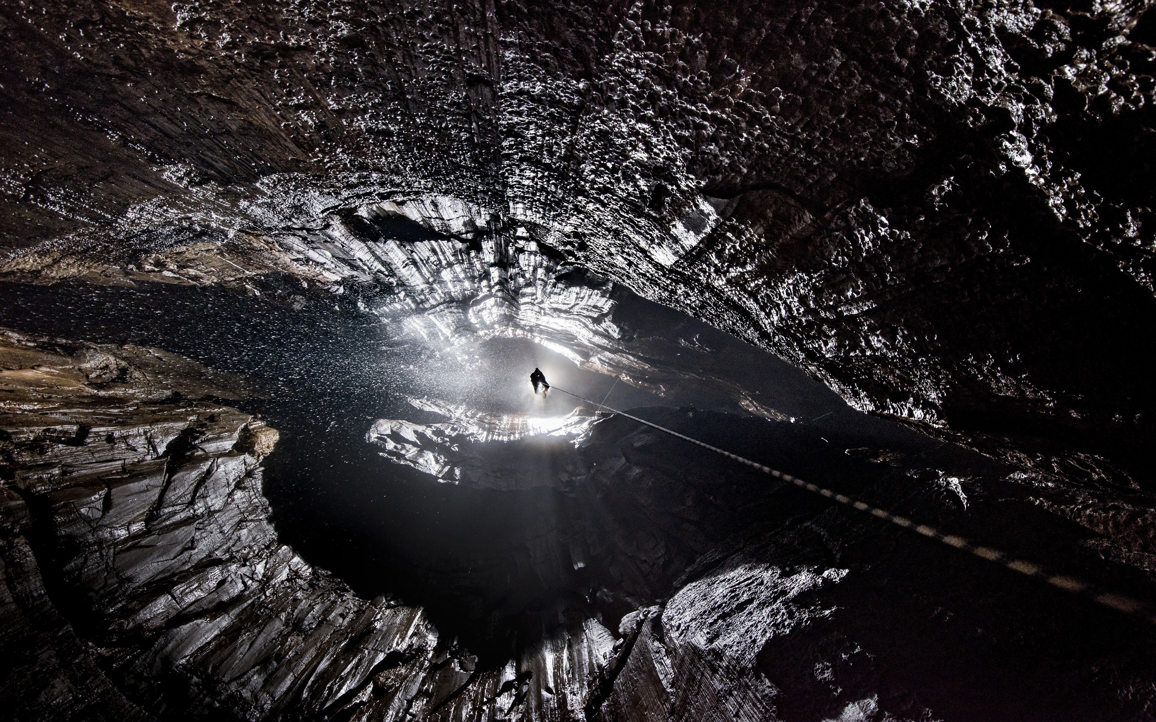 Cave with person rappelling down HD Wallpaper
