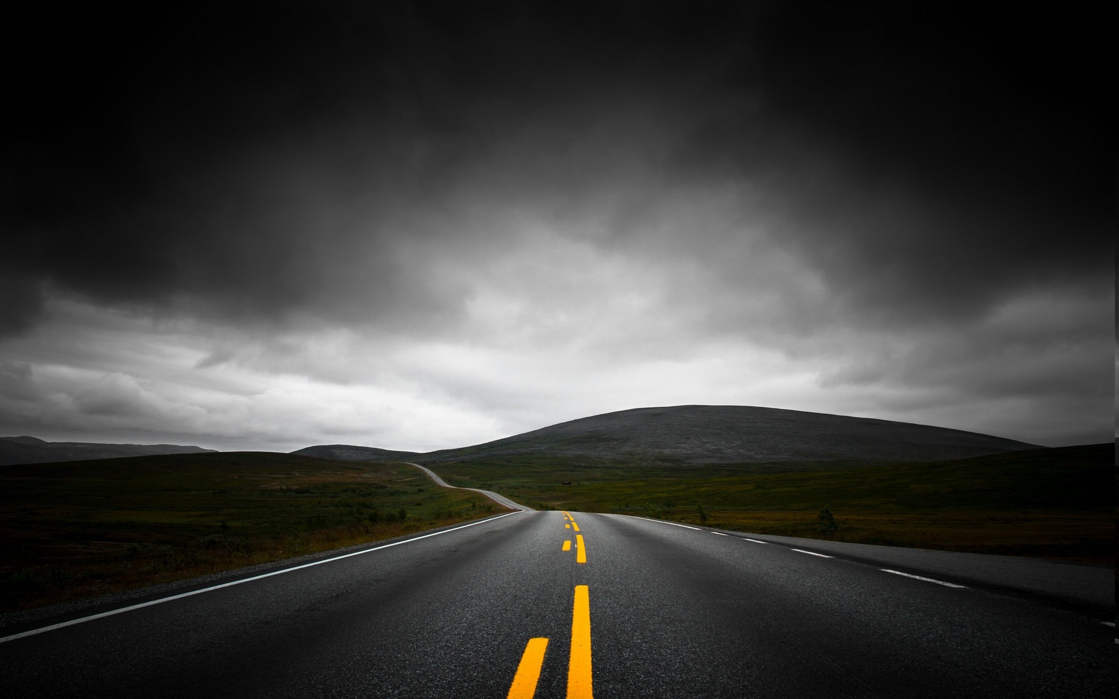 Asphalt road with yellow lines under dark clouds HD Wallpaper