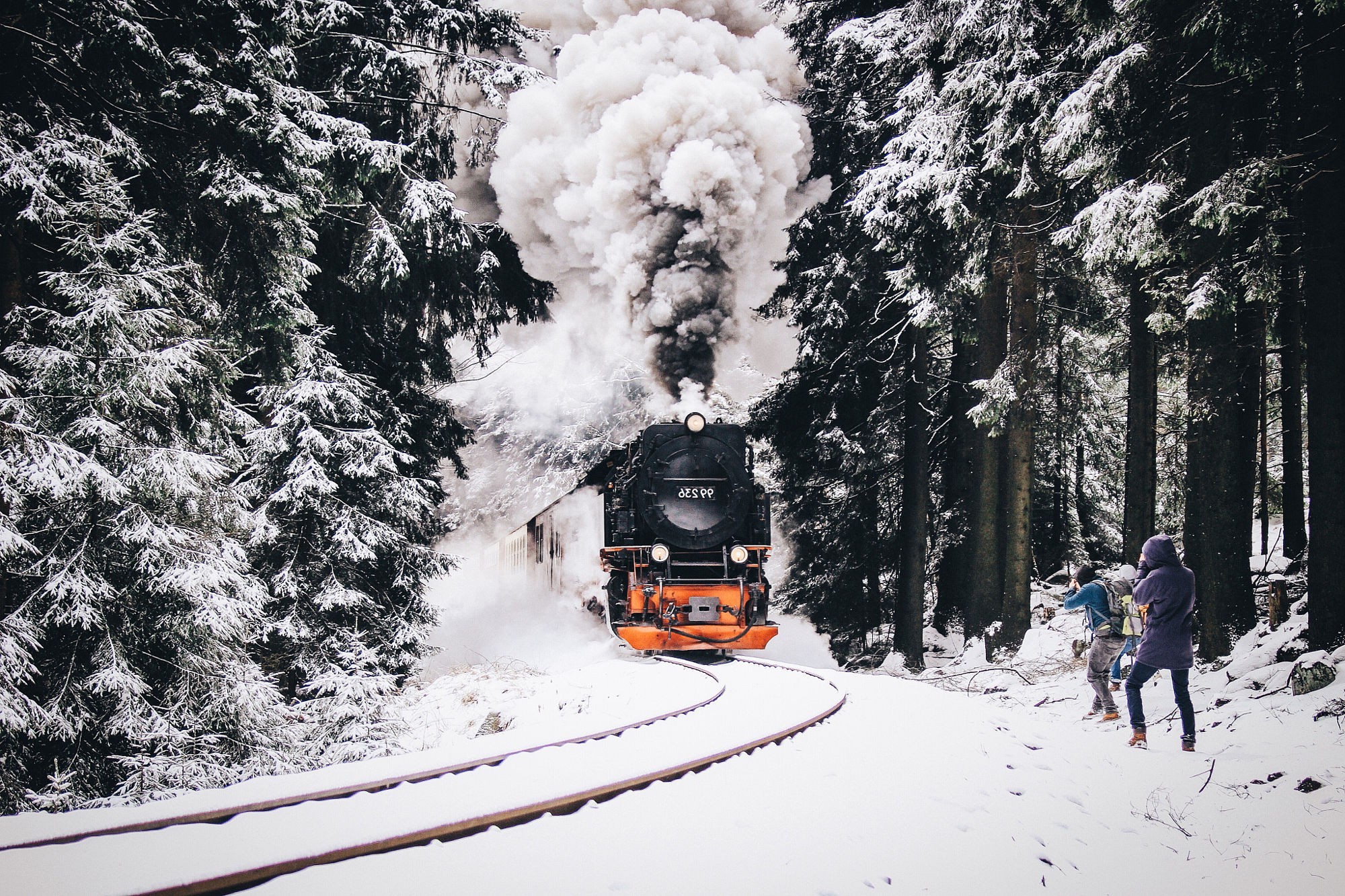 Steam train in a snowy forest with onlookers HD Wallpaper
