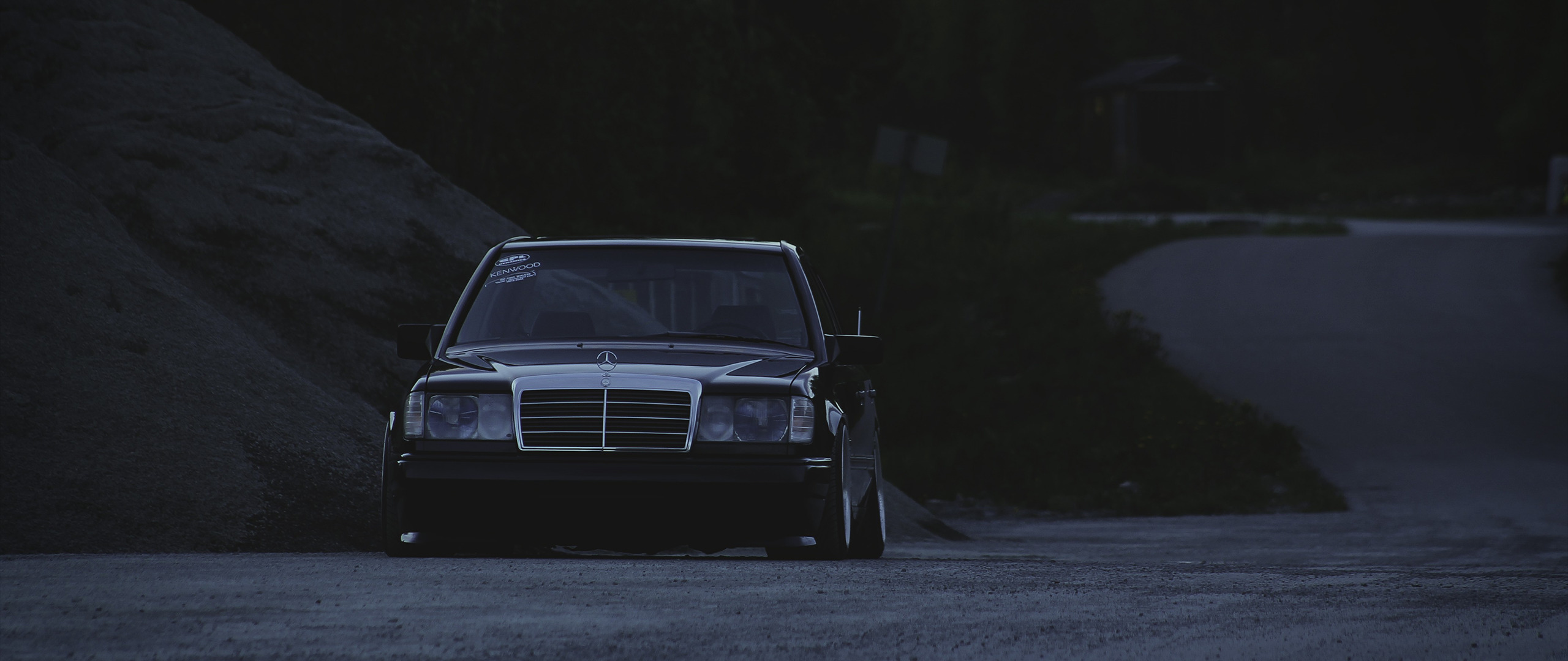 Black Mercedes-Benz W124 parked on gravel road HD Wallpaper