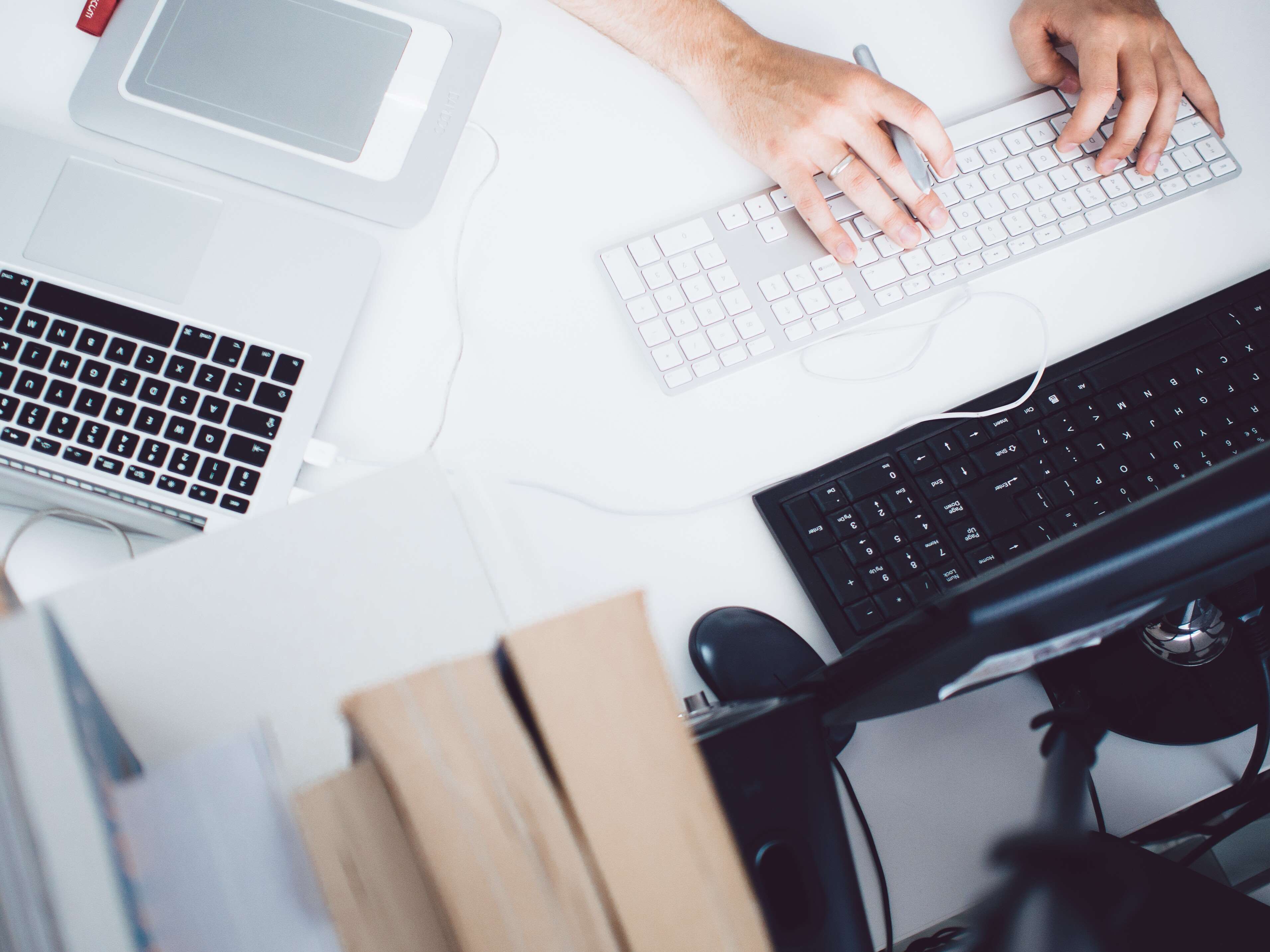 Person typing on keyboards at a desk with laptops HD Wallpaper