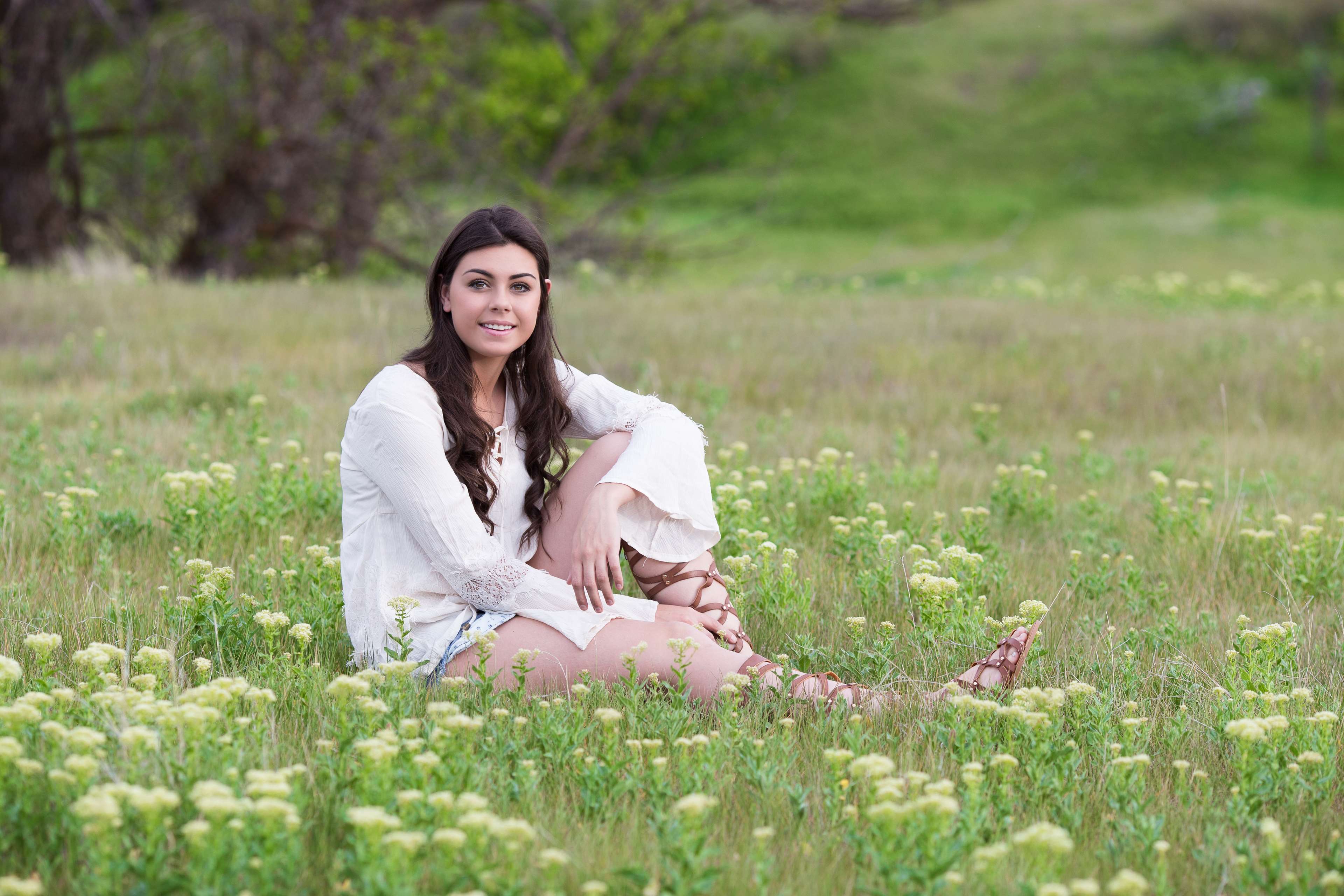 Young woman in white dress sitting in a field of flowers HD Wallpaper