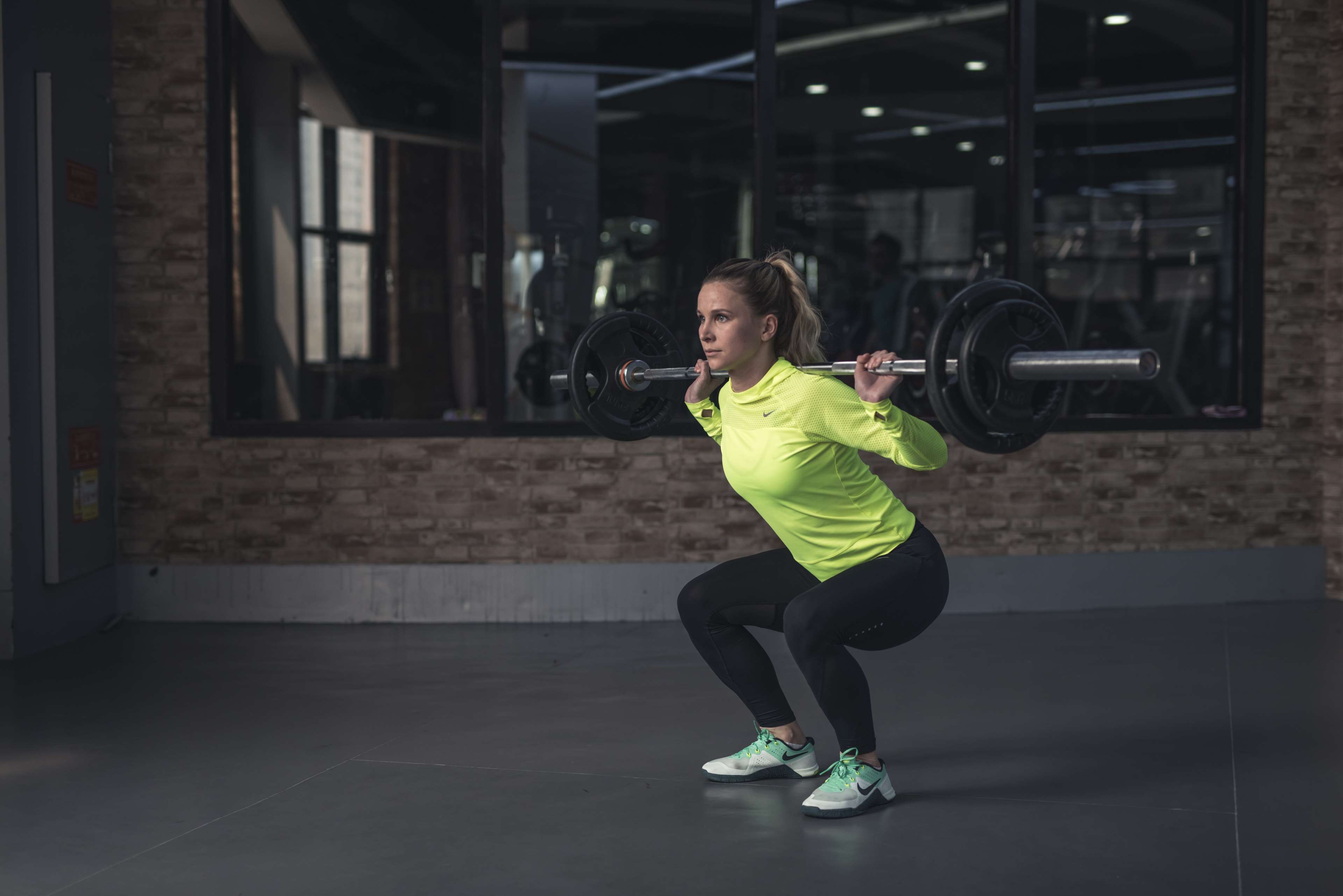 Woman performing barbell squat in gym 4K HD Wallpaper