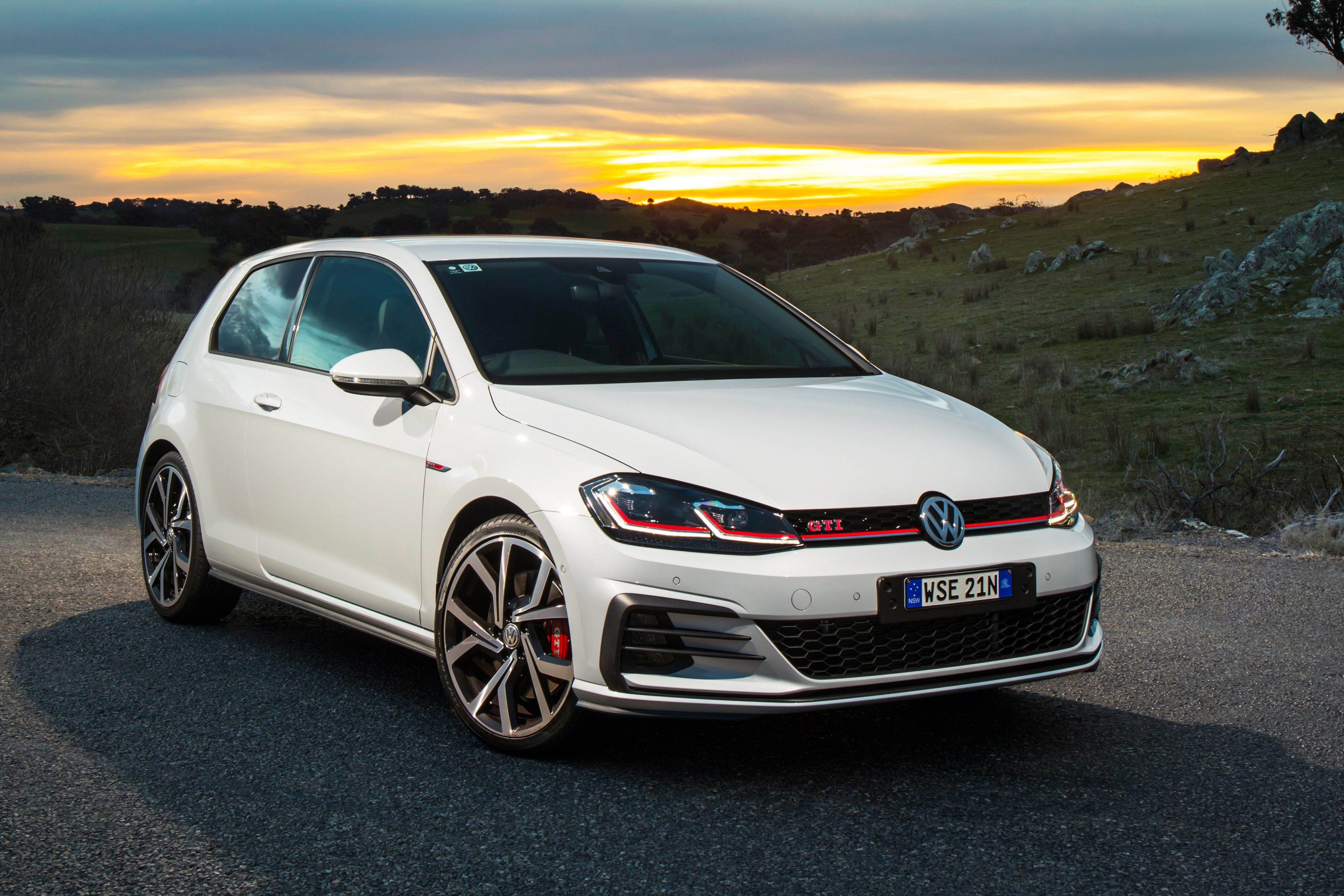 White Volkswagen Golf GTI parked on a road at sunset HD Wallpaper