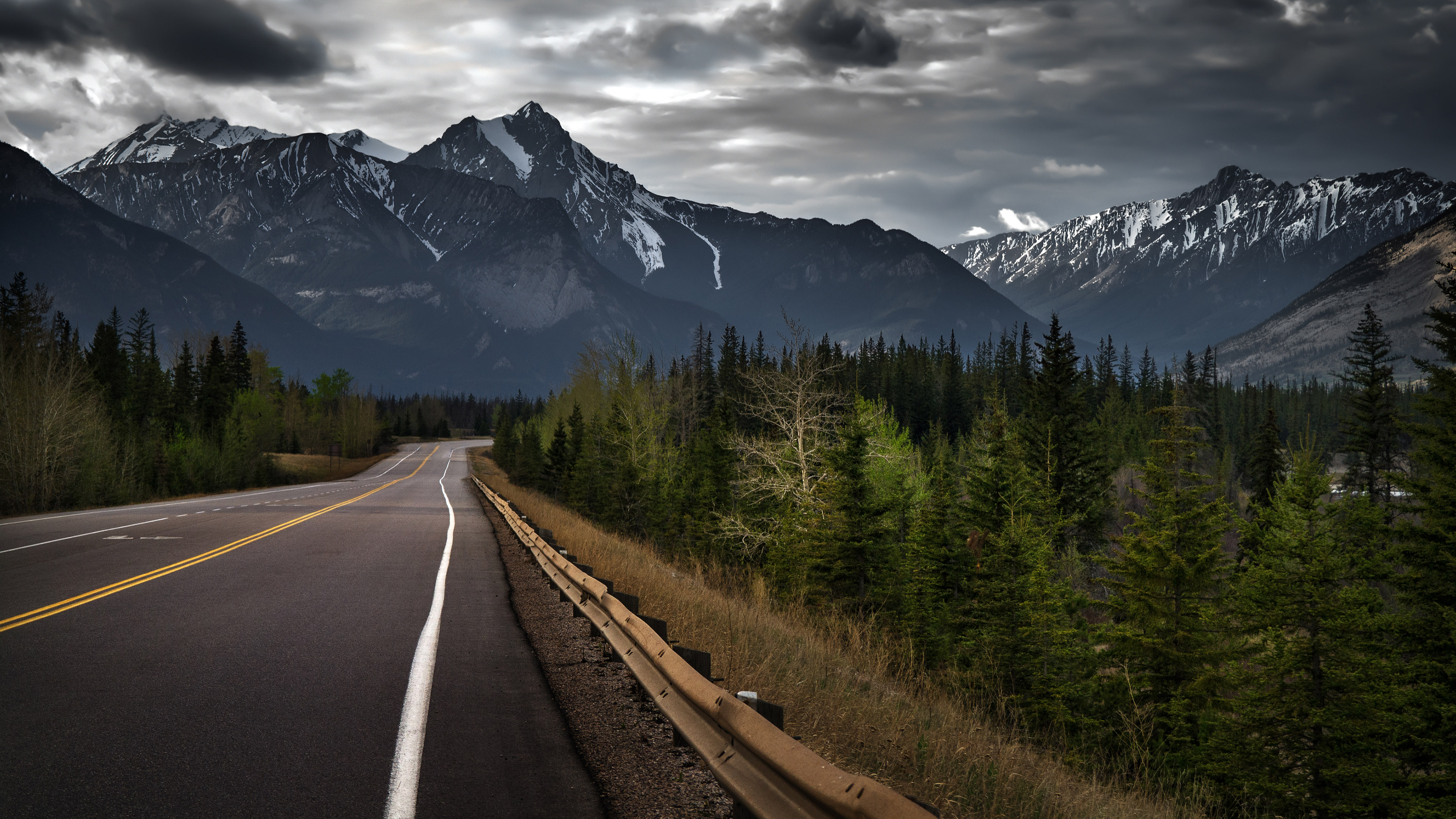 Road leading to snow-capped mountains under cloudy sky HD Wallpaper