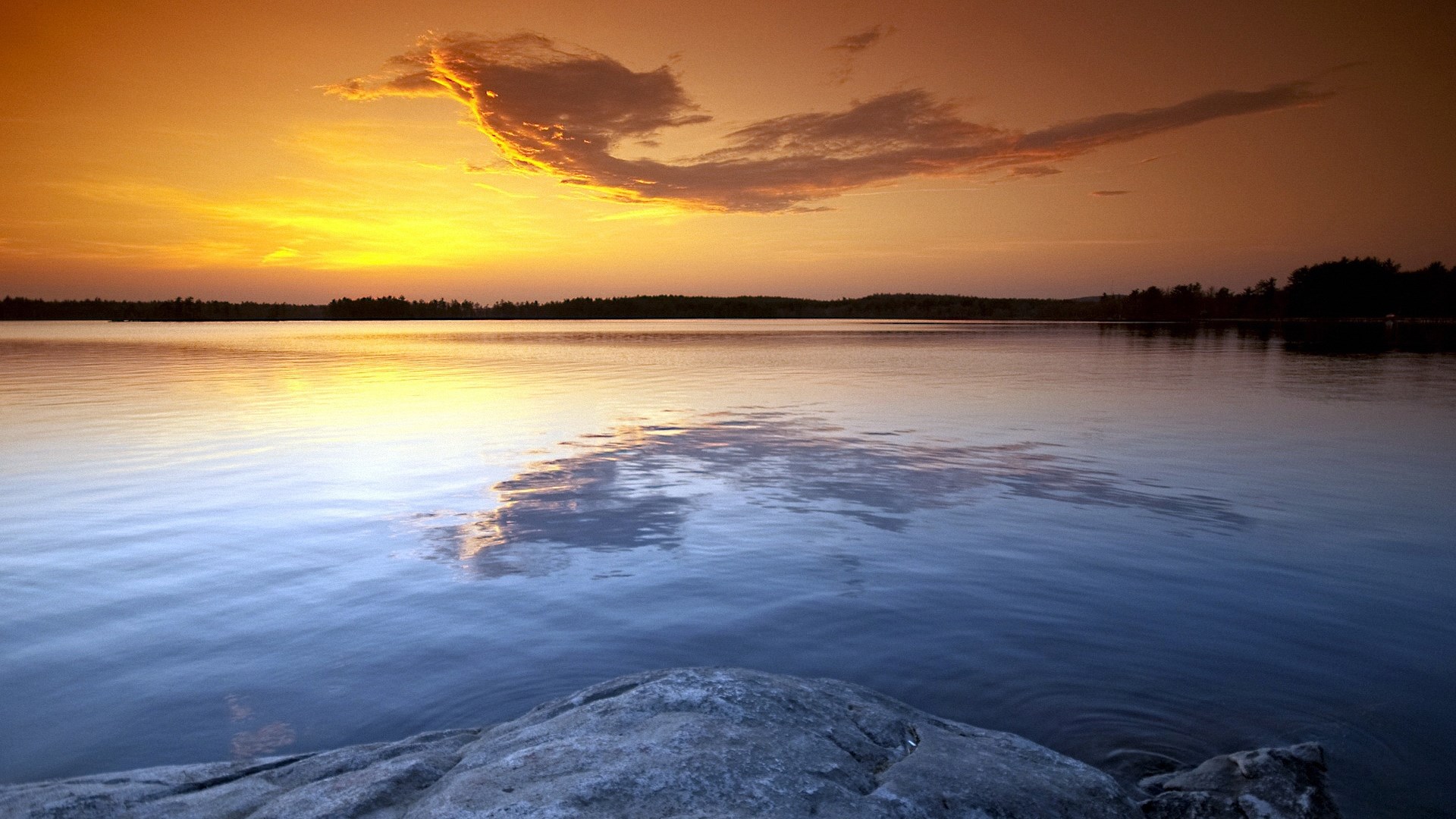 Sunset over a calm lake with a rocky shore HD Wallpaper
