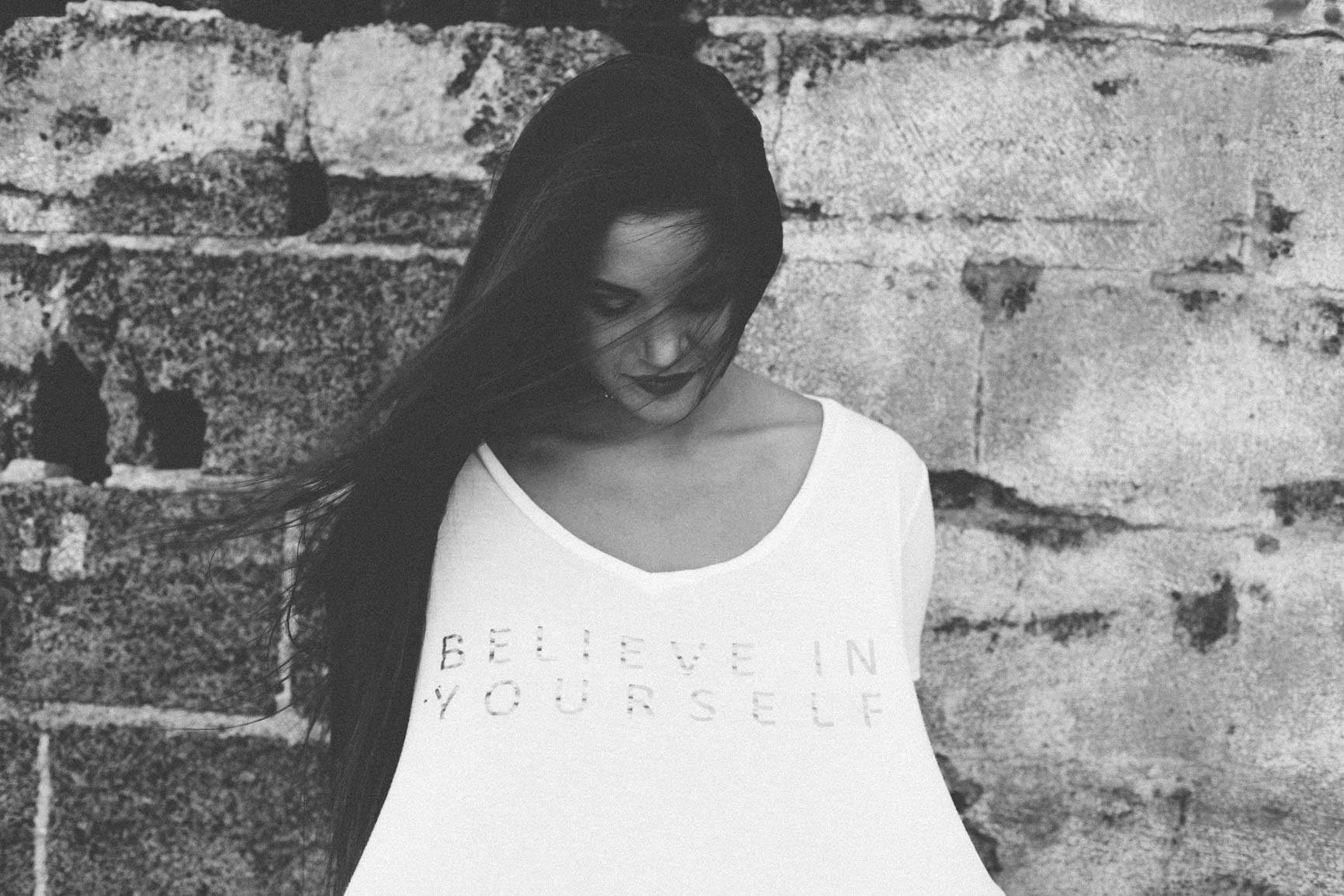 Girl in white t-shirt with text in front of brick wall HD Wallpaper