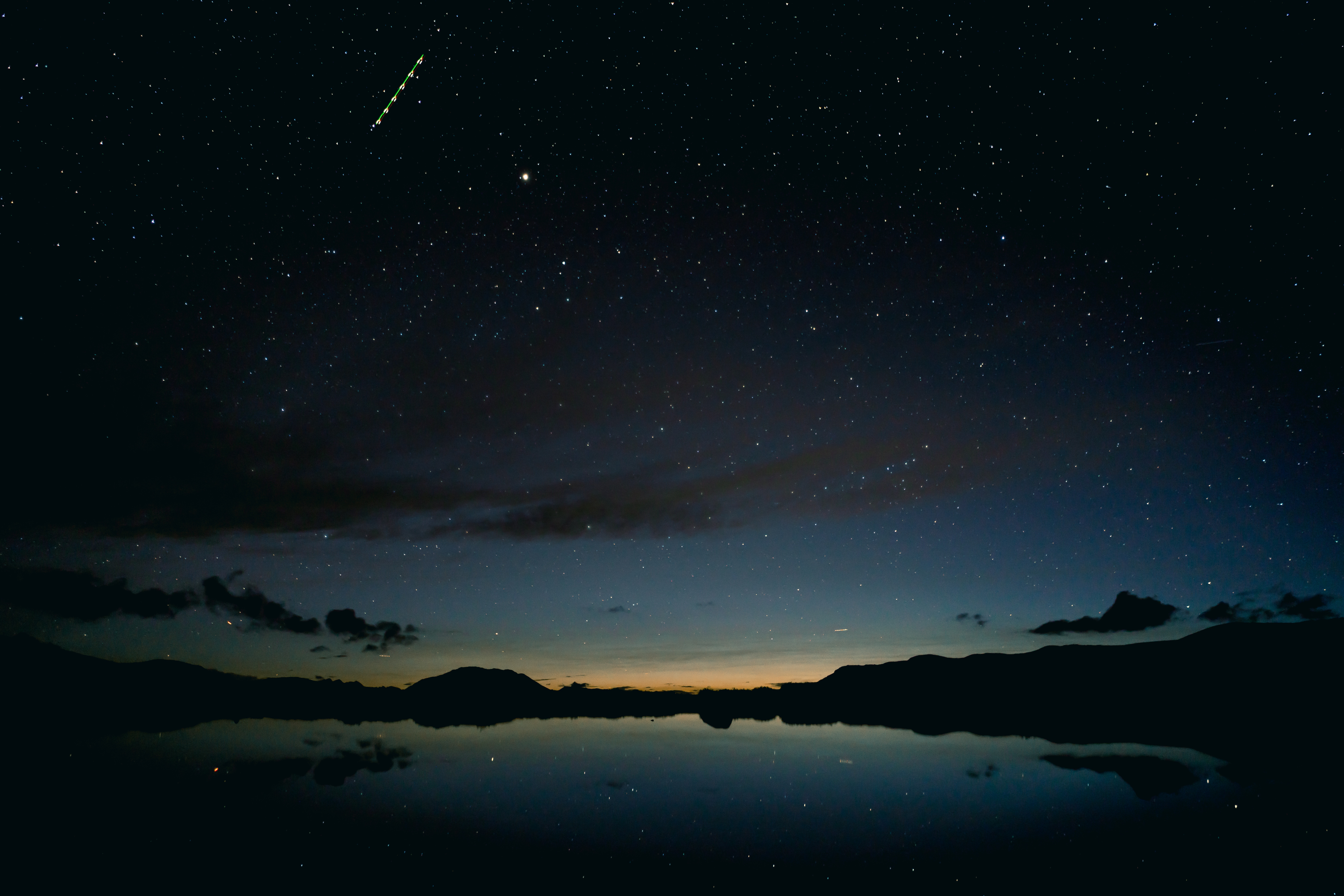 Starry night sky over a lake with mountain reflections HD Wallpaper