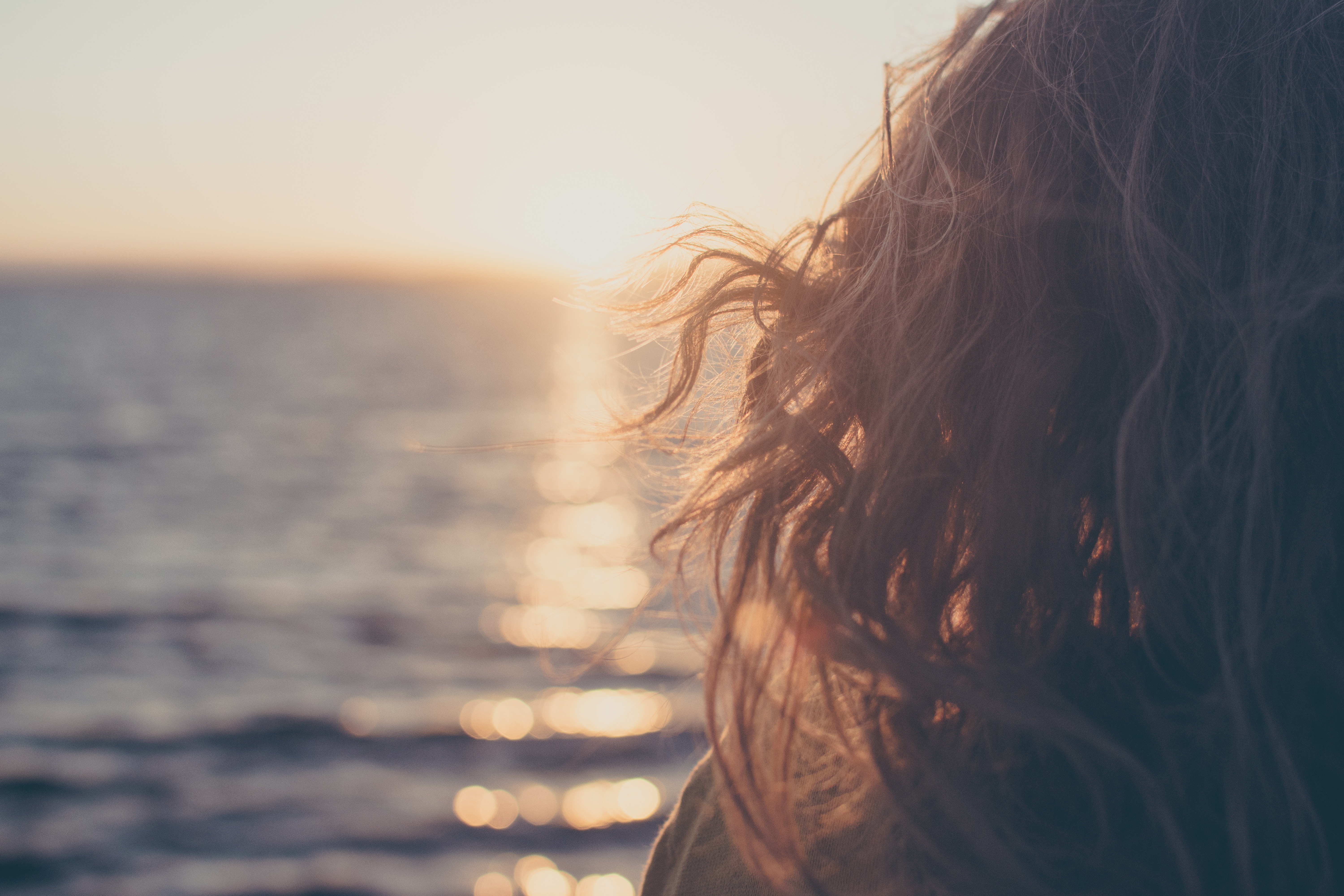 Woman's hair blowing in the wind at sunset over the sea HD Wallpaper