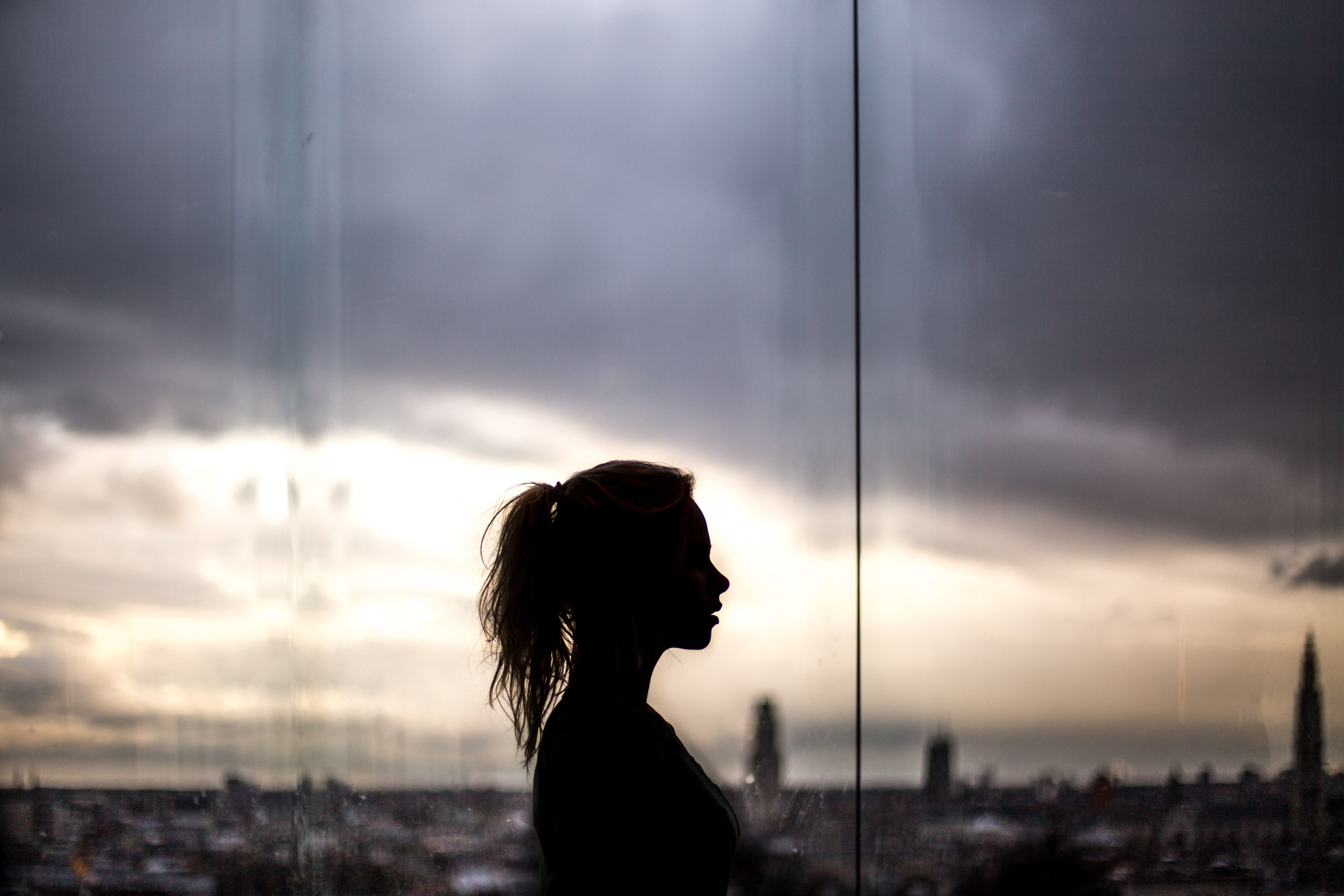 Silhouette of a woman against a stormy cityscape HD Wallpaper