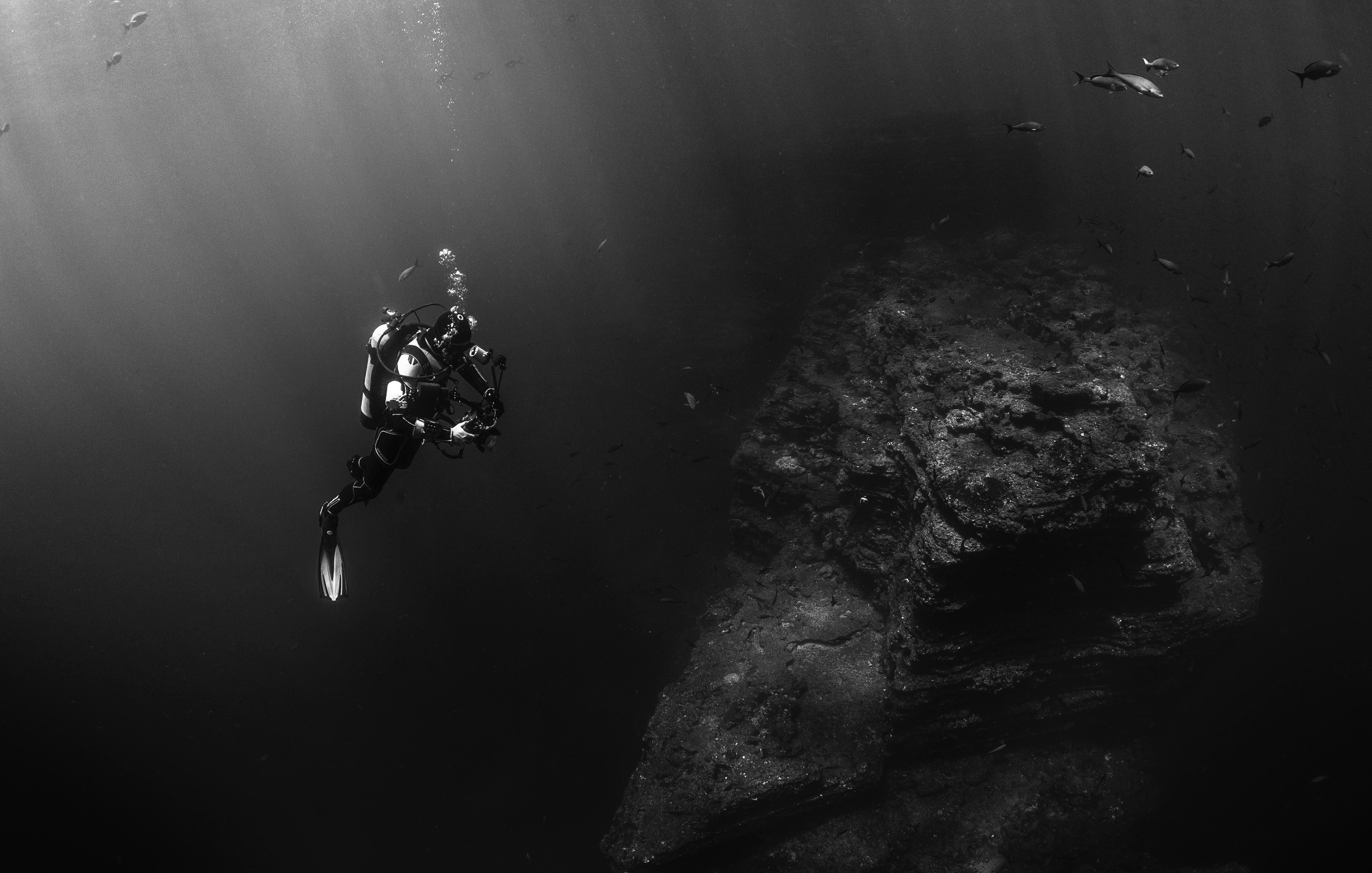 Scuba diver near a large rock formation underwater HD Wallpaper