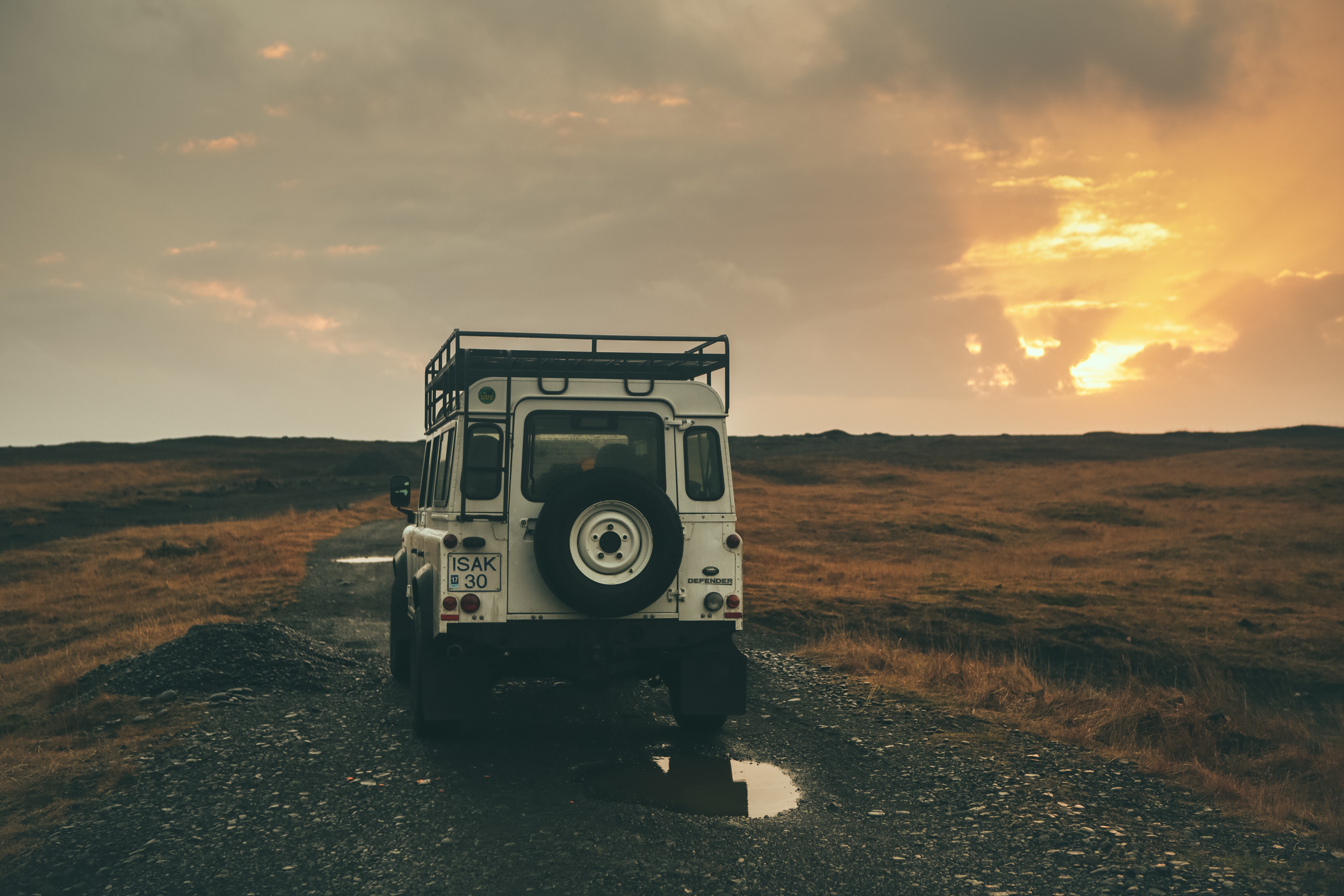 White Land Rover Defender on a dirt road at sunset in Iceland HD Wallpaper