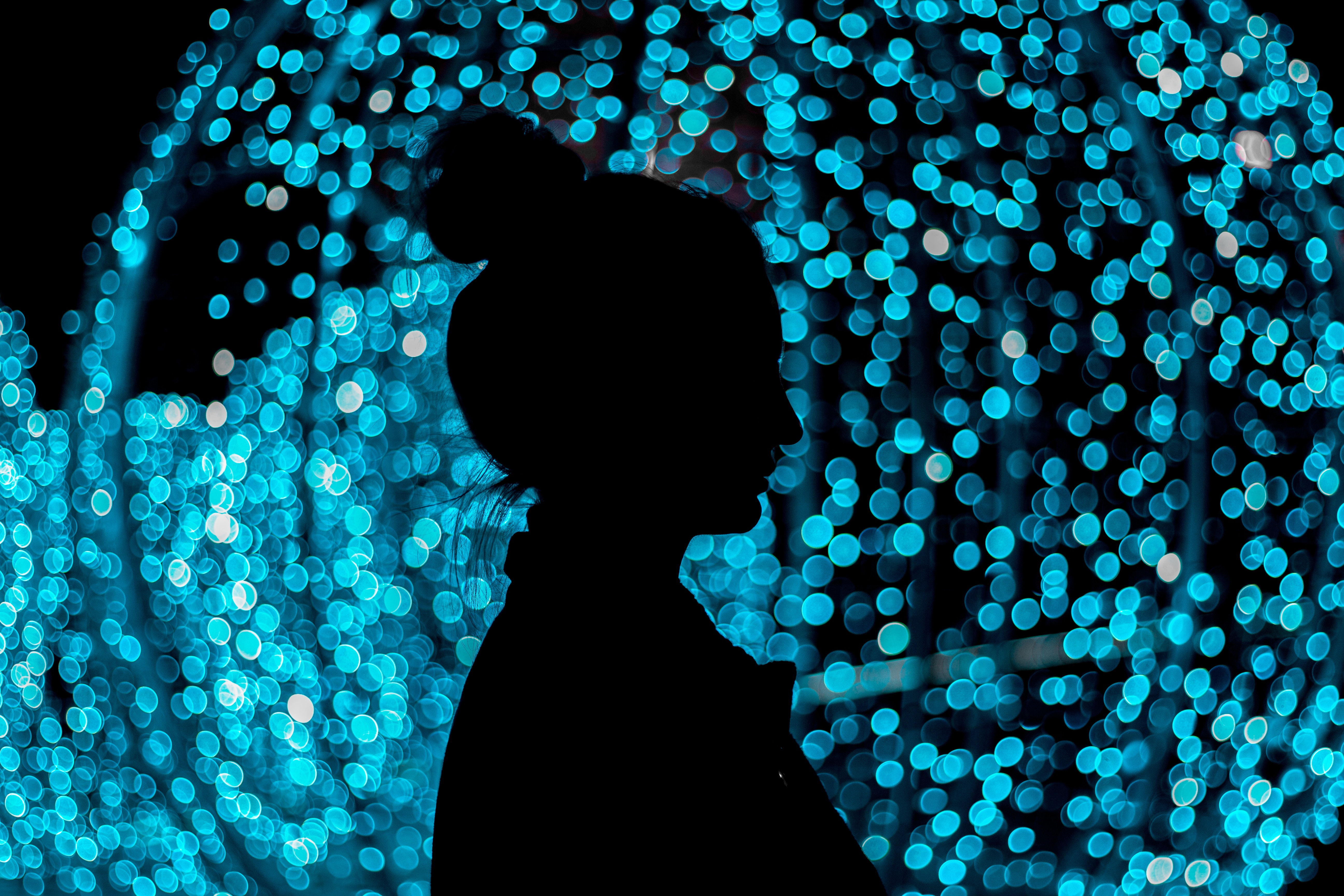Silhouette of a woman against blue bokeh lights HD Wallpaper