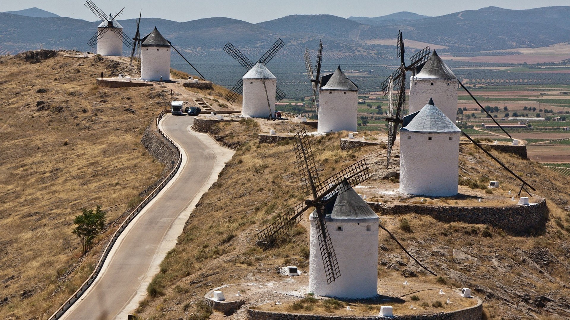Windmills on a hill with a road and fields HD Wallpaper
