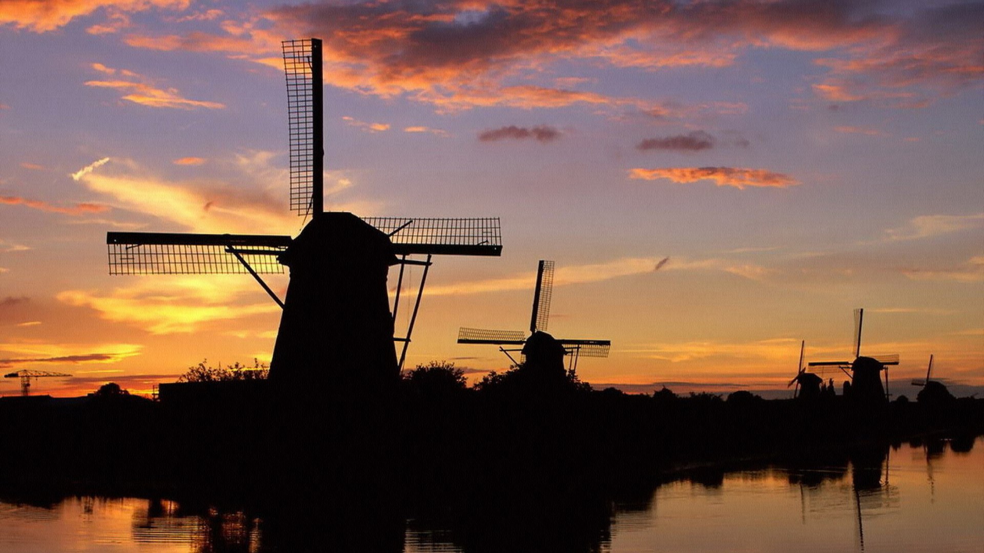 Windmills silhouetted against a sunset sky HD Wallpaper