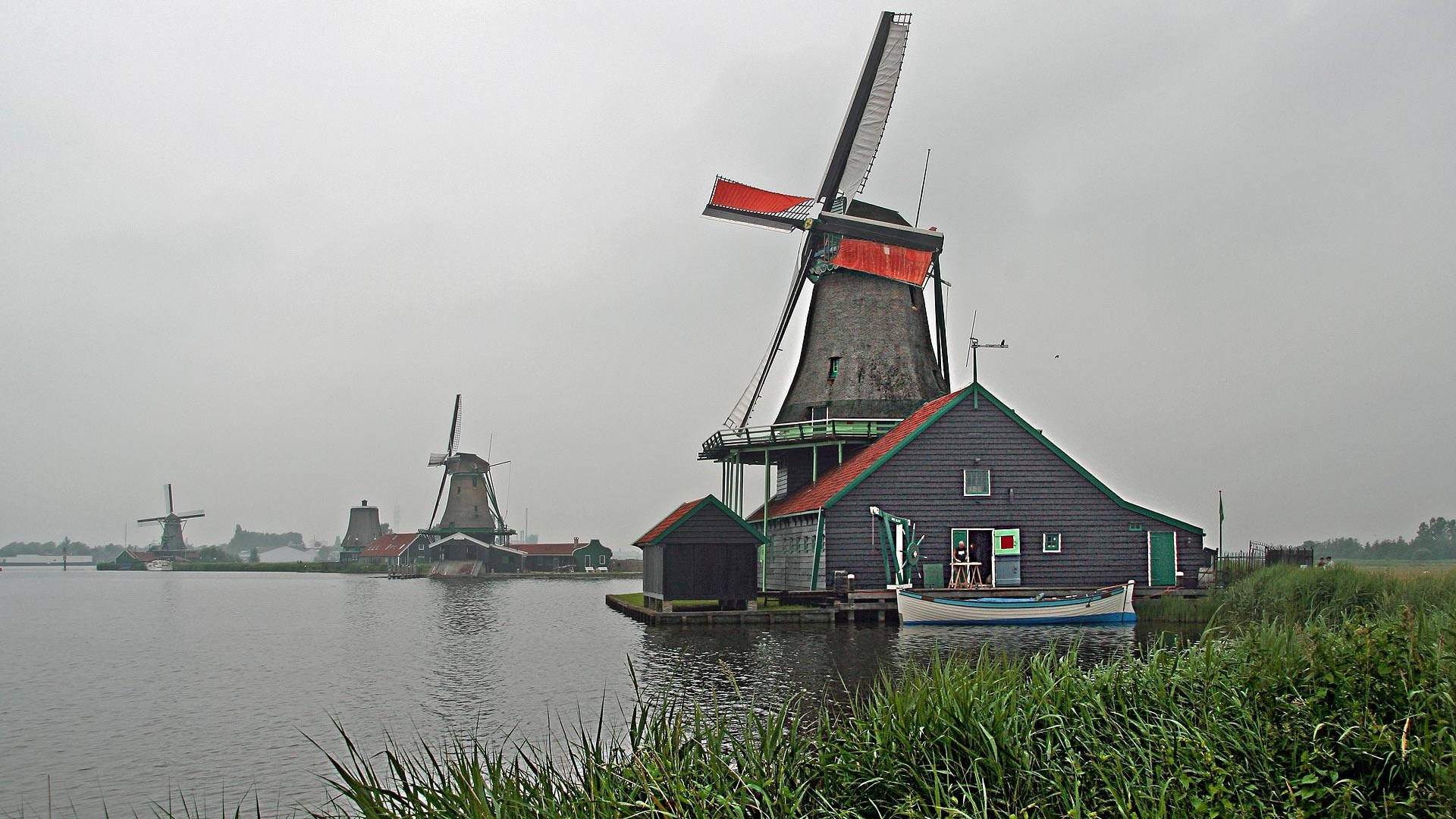 Windmills on a cloudy day by the water HD Wallpaper