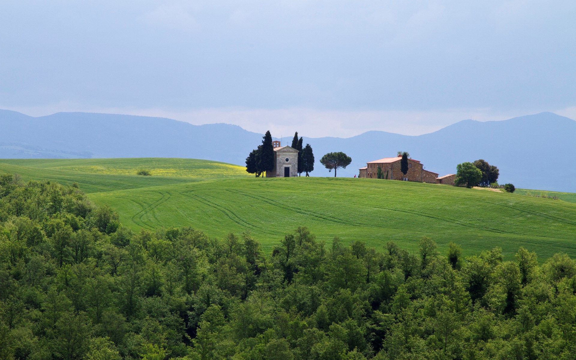 Chapel and farmhouse on rolling green hills in Tuscany HD Wallpaper