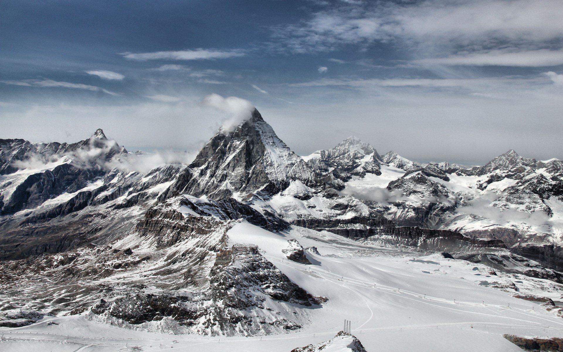 Snow-covered mountains under a cloudy sky HD Wallpaper