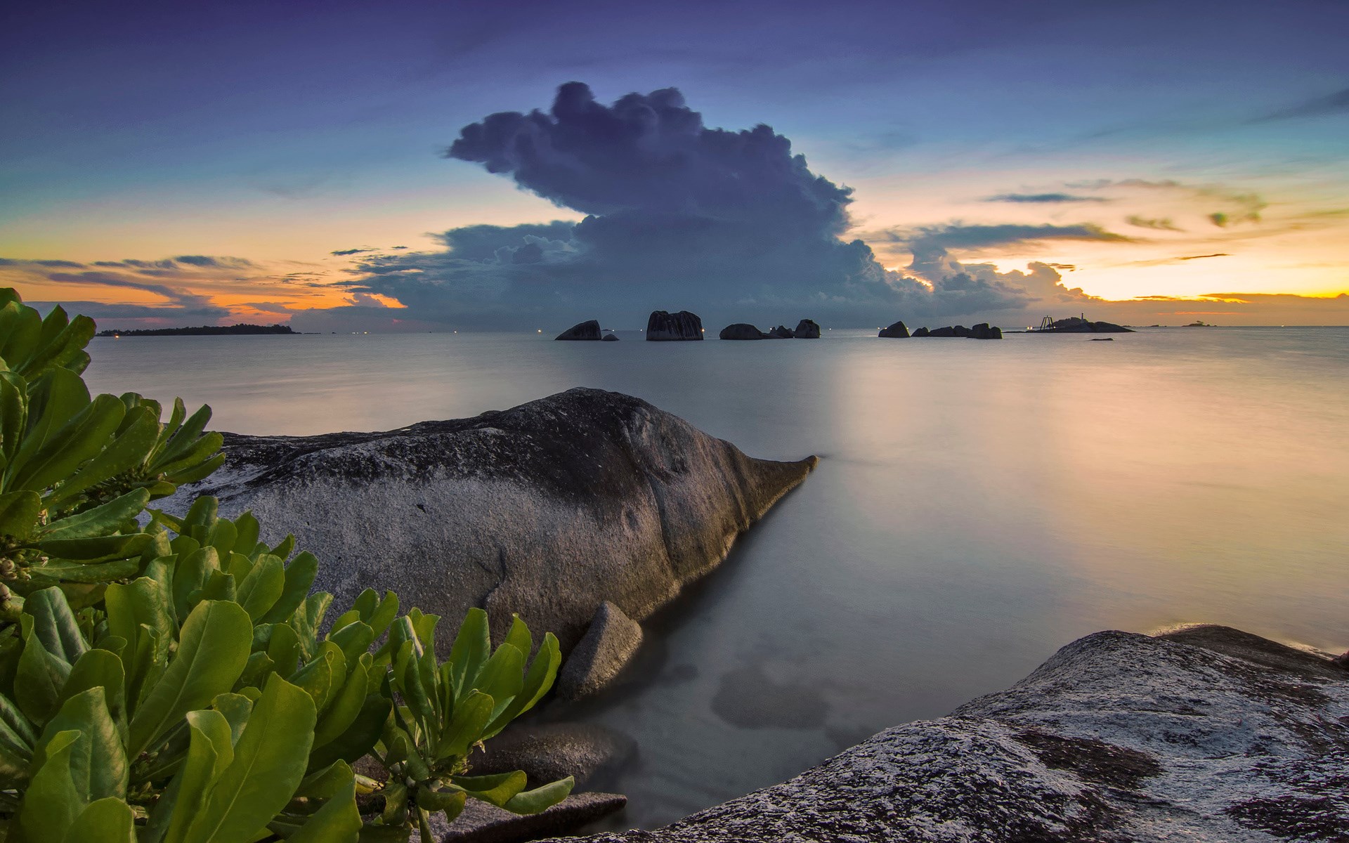 Rocky beach at sunset with calm sea and dramatic clouds HD Wallpaper