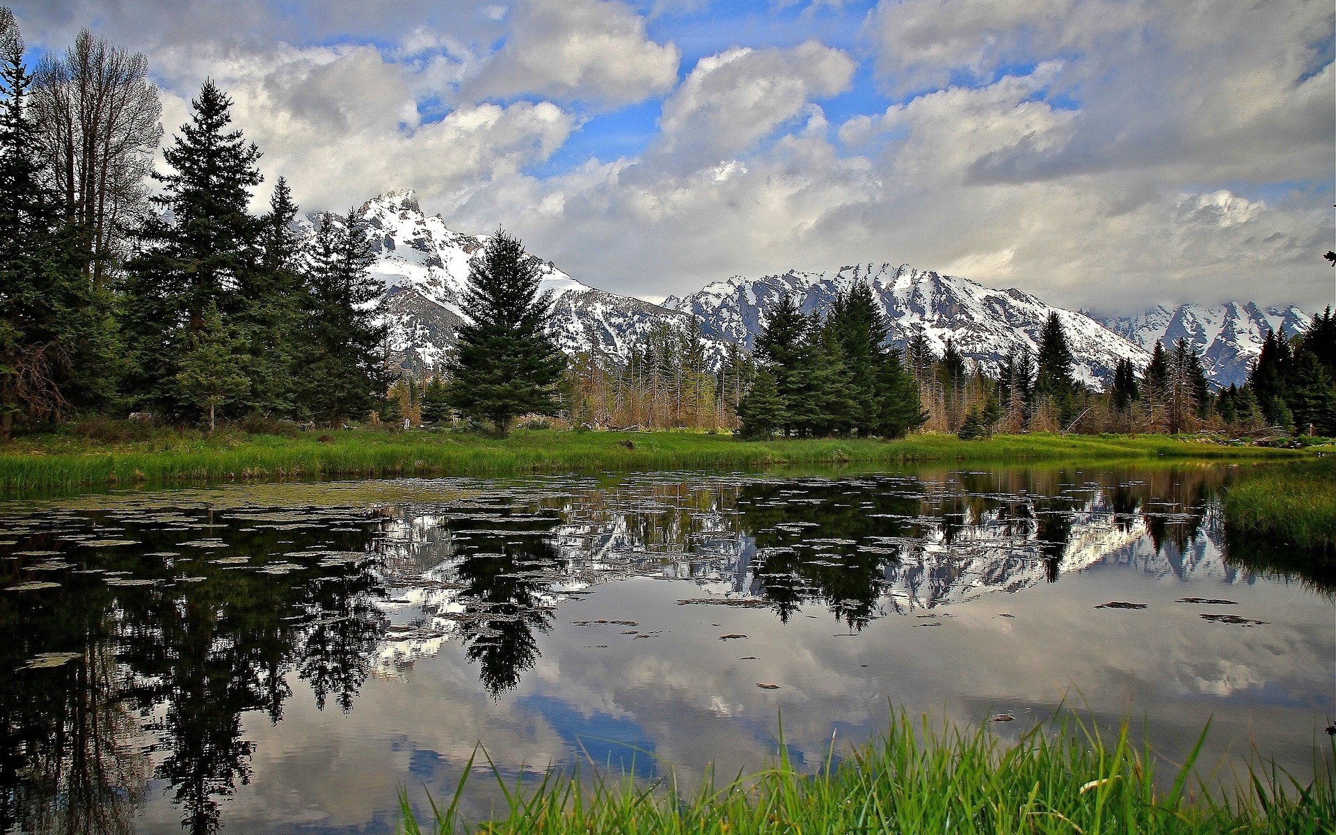 Mountain range reflected in a calm lake with trees HD Wallpaper
