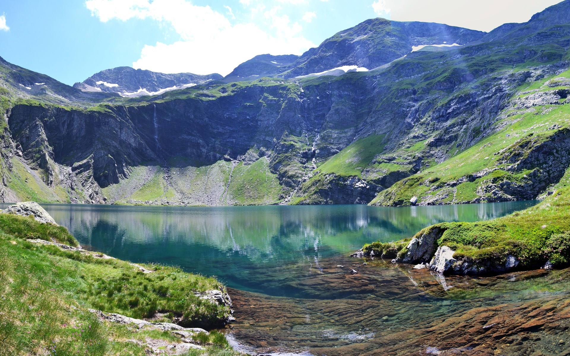 Mountain lake with rocky shore and green slopes HD Wallpaper