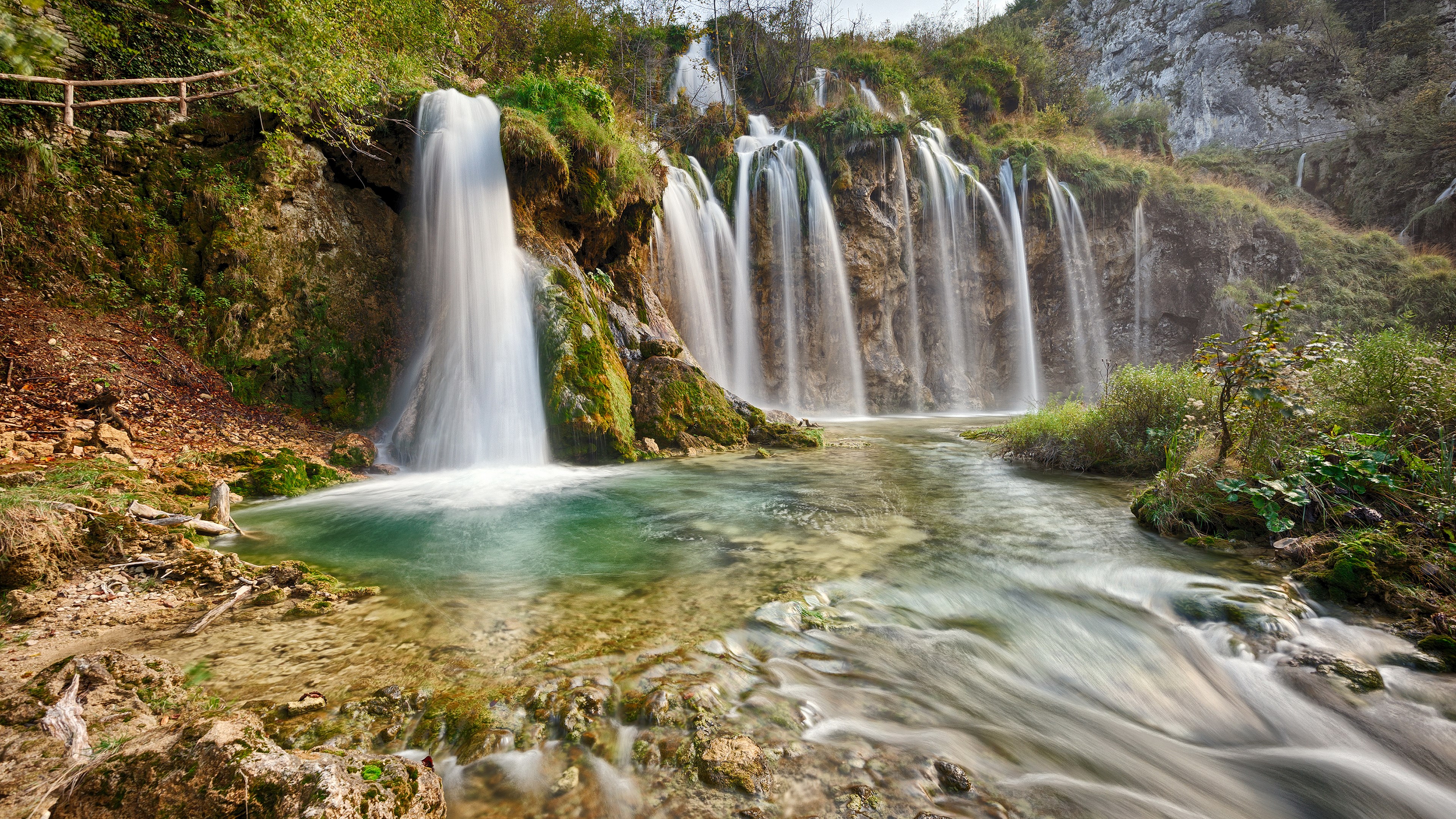 Waterfalls cascading into a turquoise pool in a forest HD Wallpaper