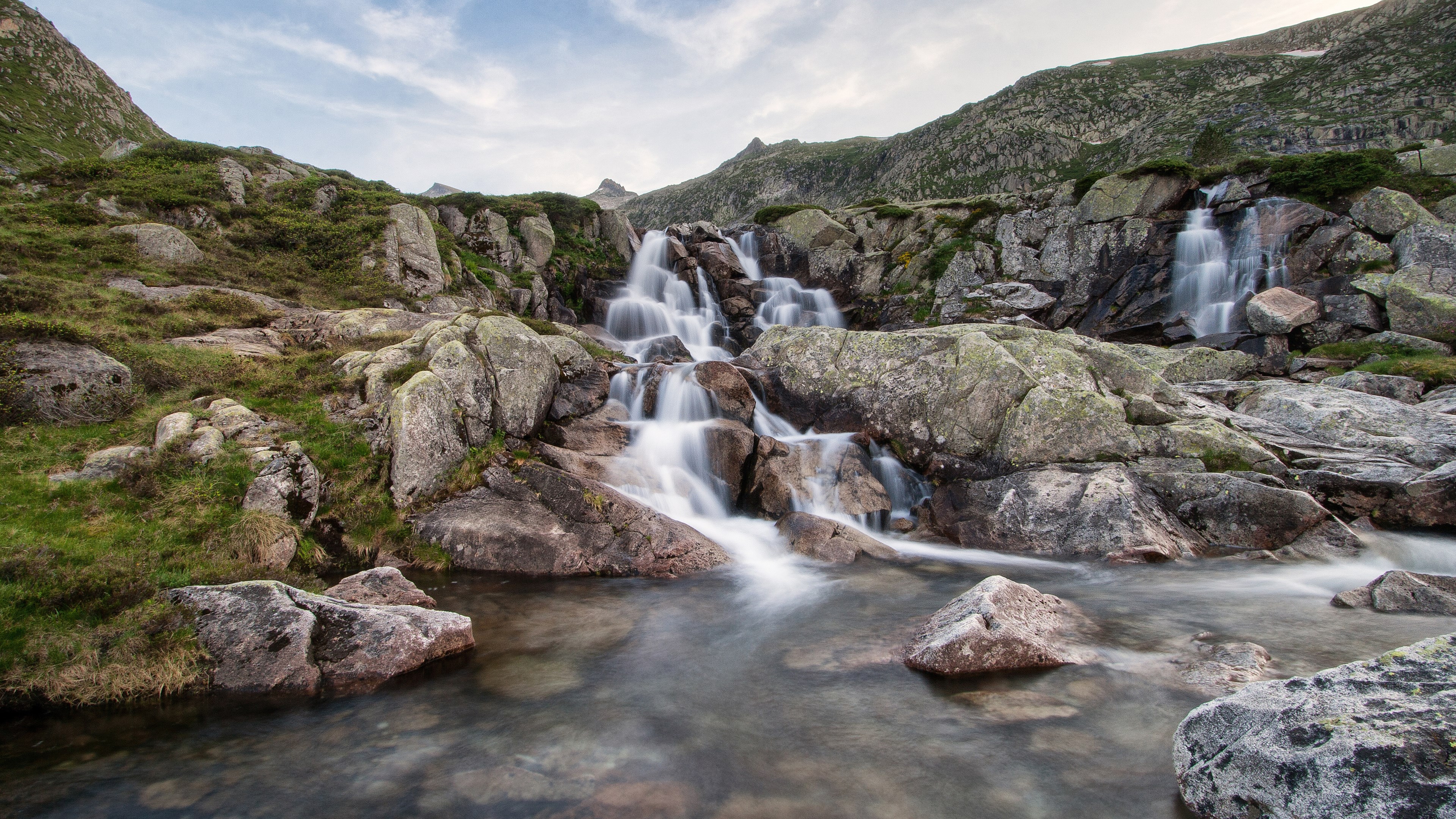 Rocky mountain waterfall with smooth water flow HD Wallpaper