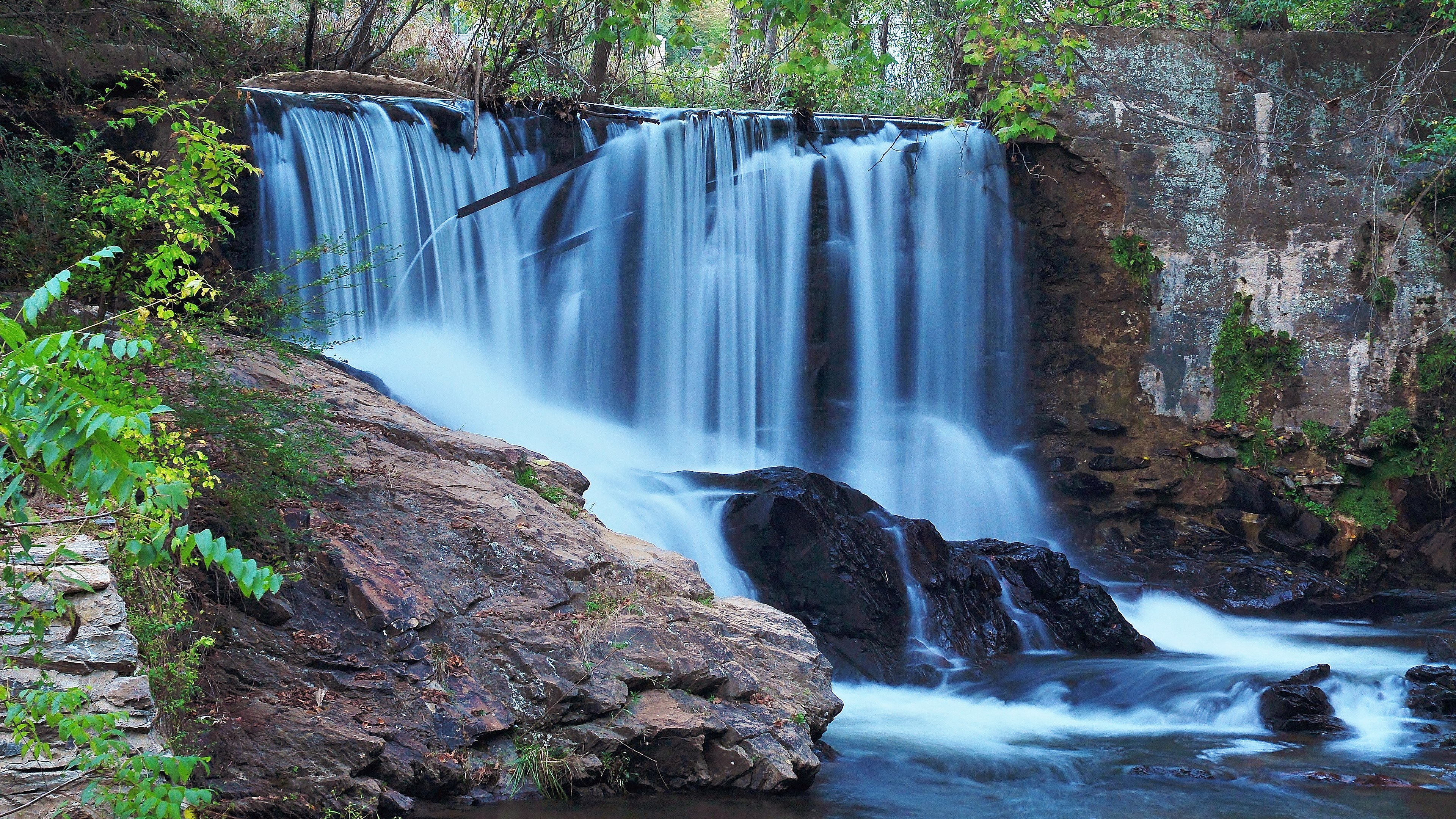Waterfall cascading over rocks and concrete structure HD Wallpaper