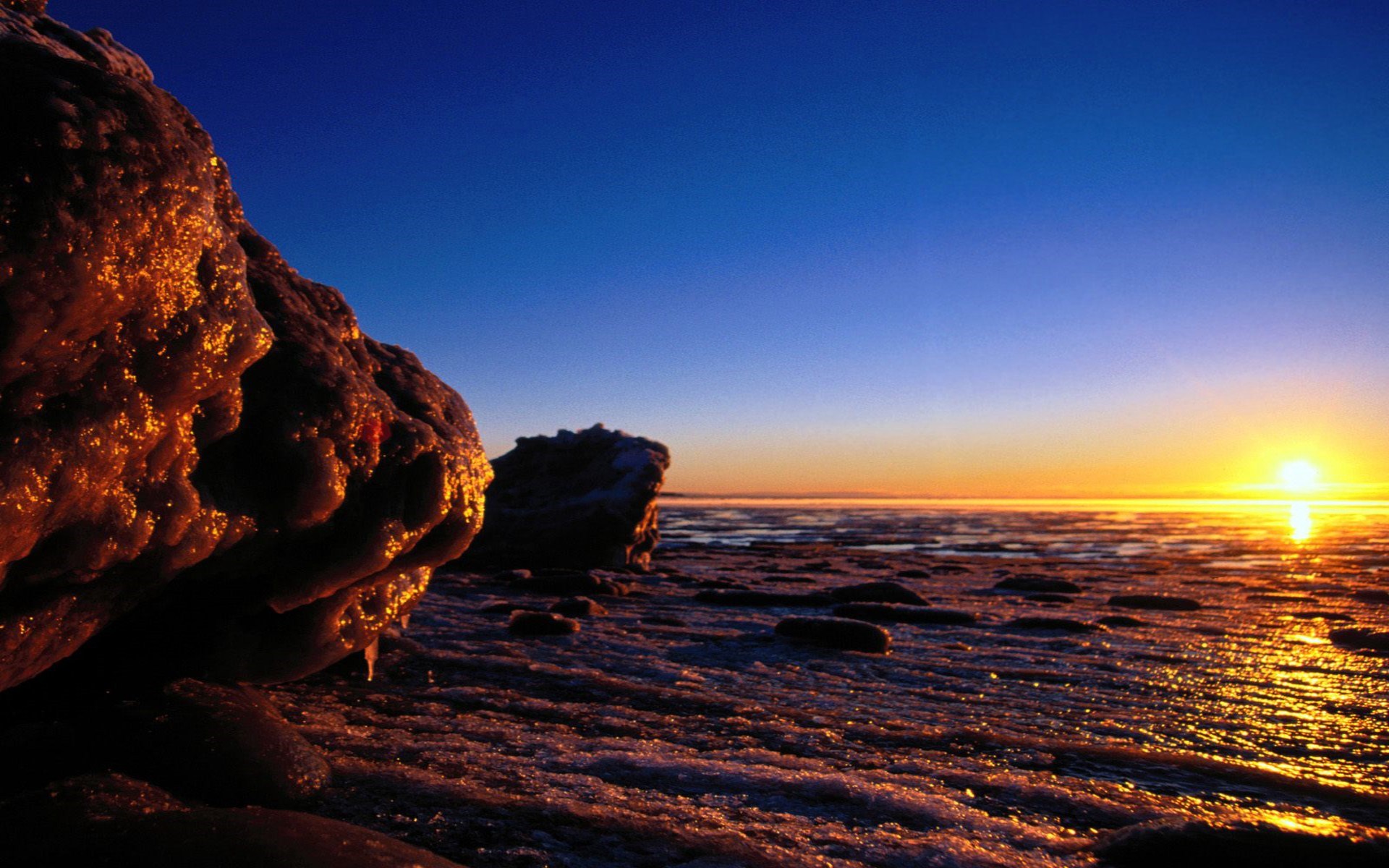 Frozen rocks and icy shore at sunset HD Wallpaper