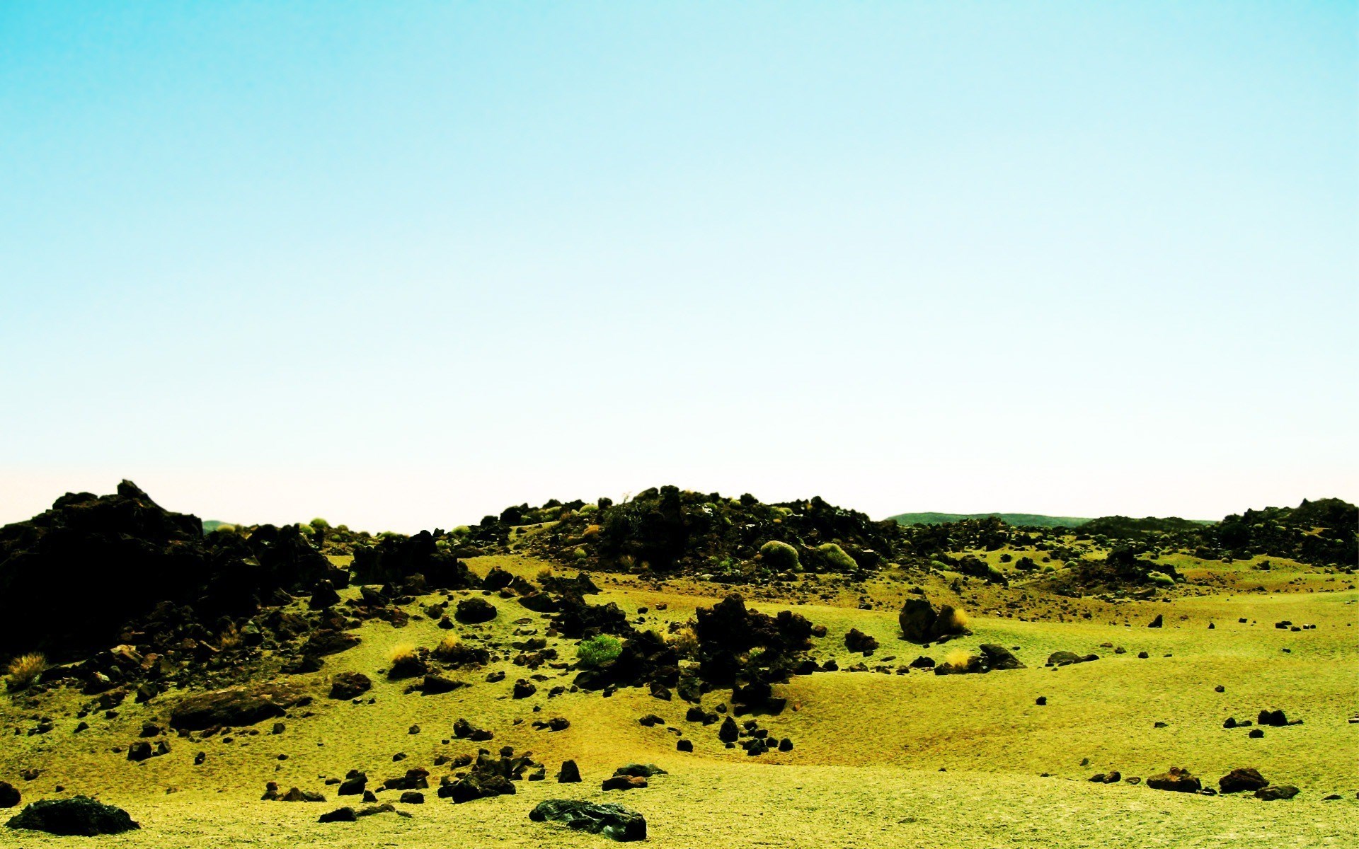 Rocky, grassy landscape under a clear blue sky HD Wallpaper