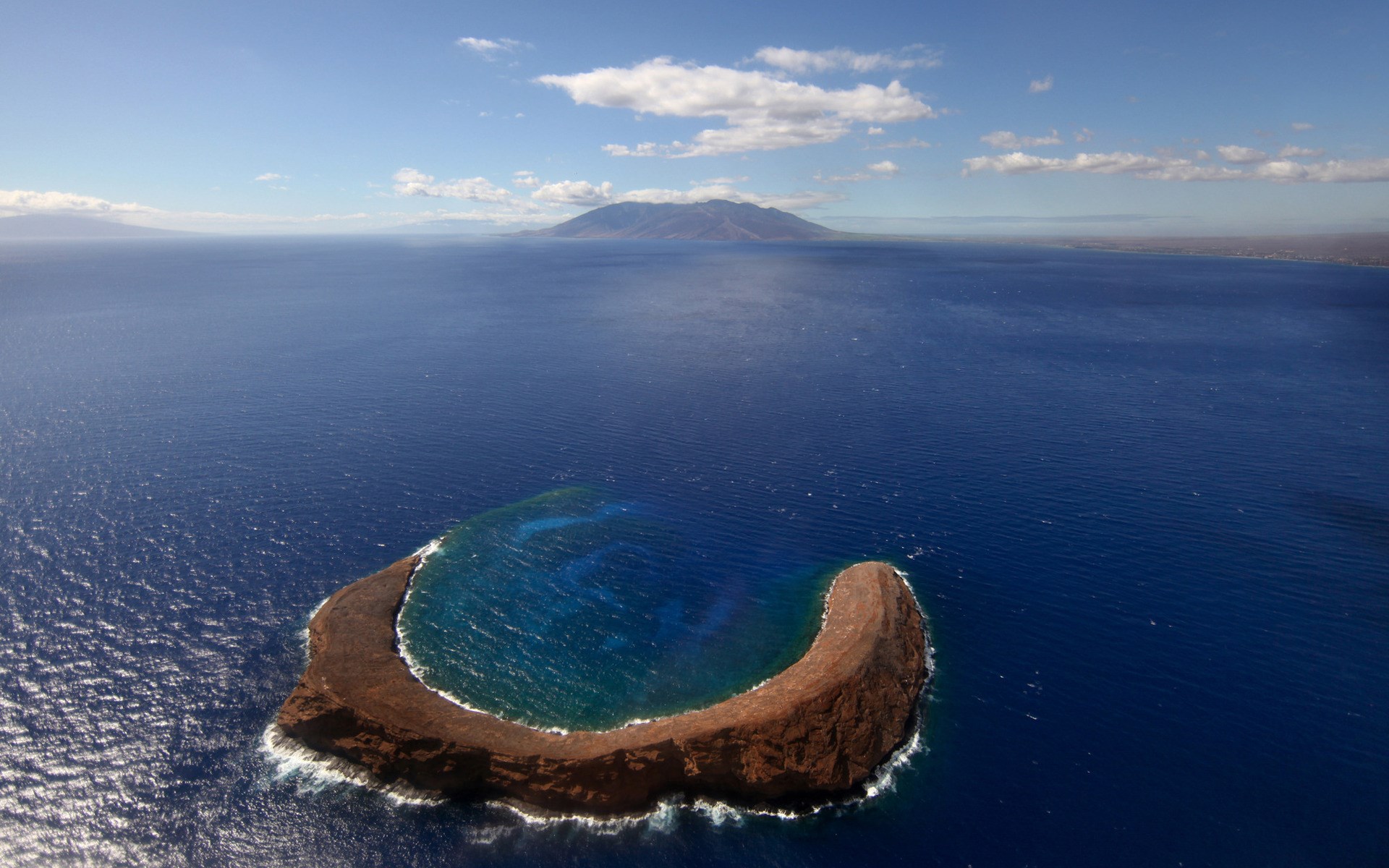 Island in the ocean with distant mountains HD Wallpaper