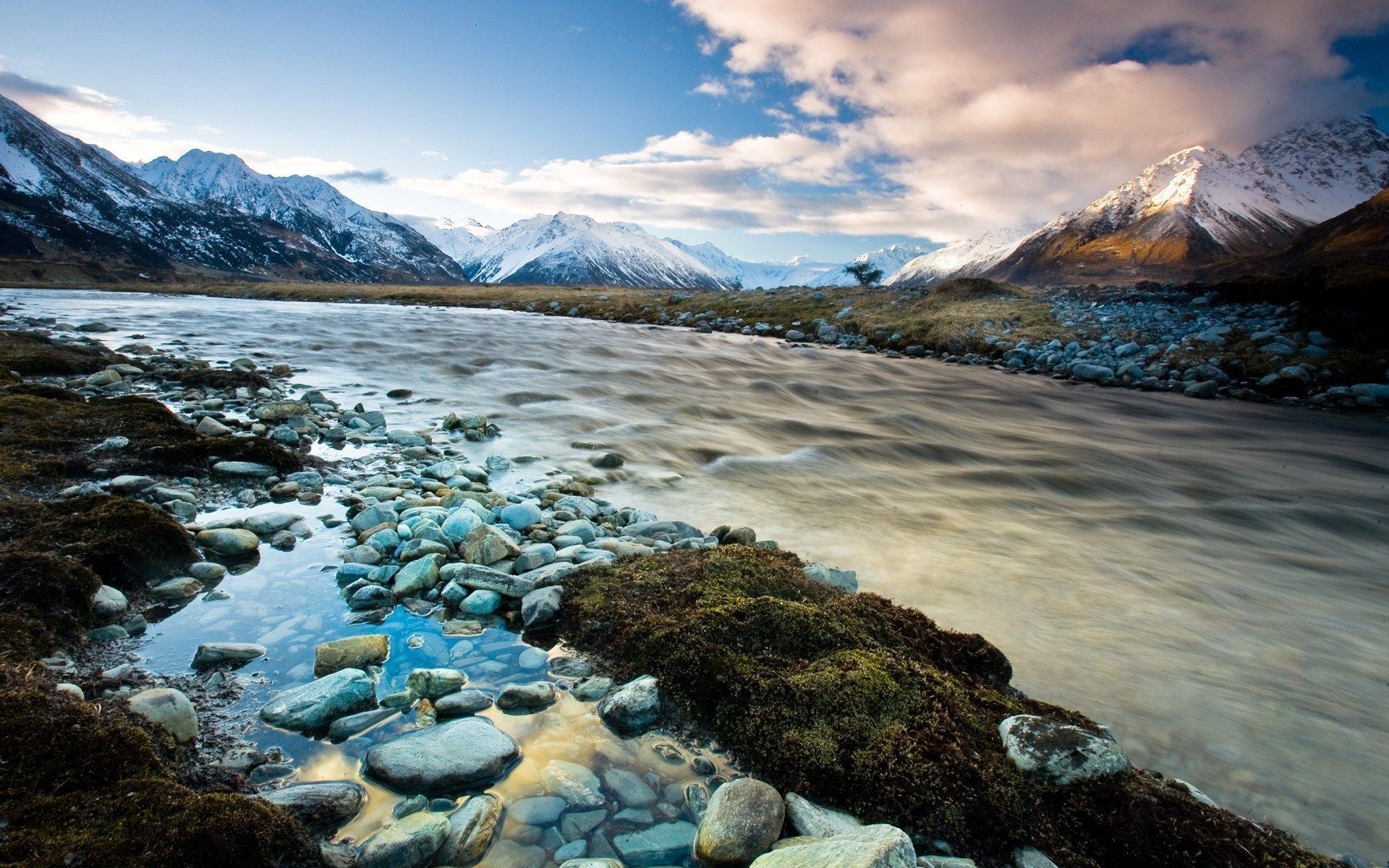 River flowing through a rocky valley with snow-capped mountains HD Wallpaper