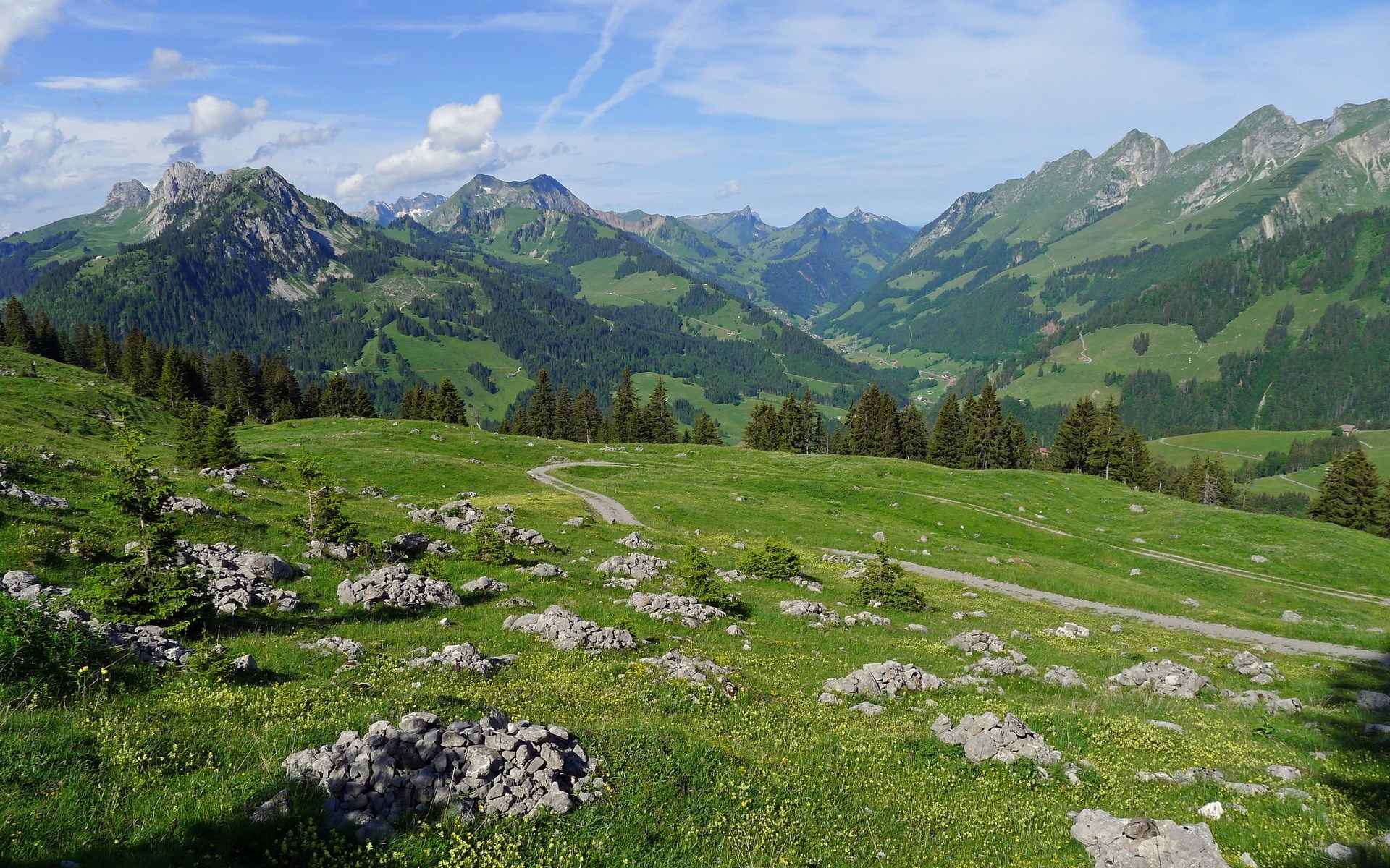 Mountain valley with green hills and rocky foreground HD Wallpaper