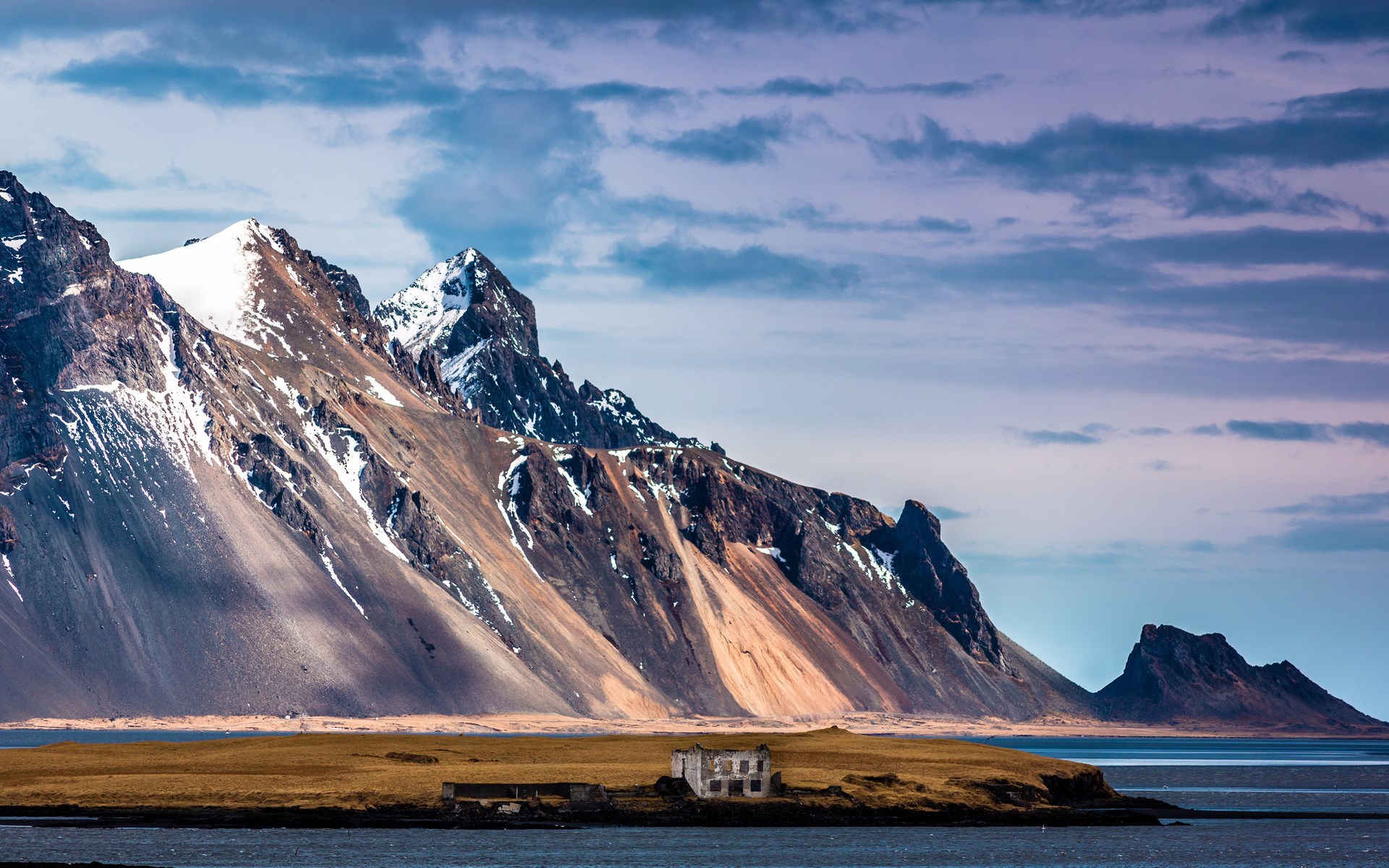 Ruined building on a grassy island with mountains and sea HD Wallpaper